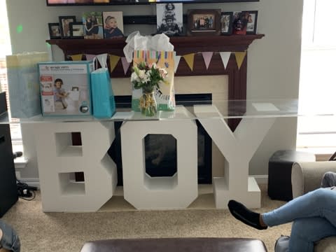 Small flower arrangement beside a large white "BOY" decoration