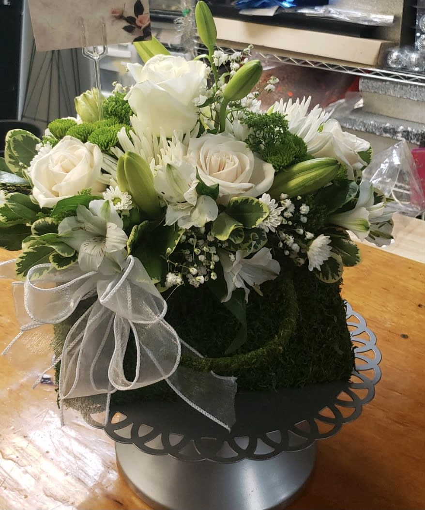 White roses and lilies arranged in a round box with a white ribbon