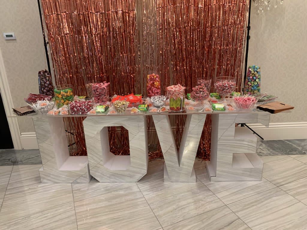 Candy display on a large LOVE sign with a rose-gold backdrop