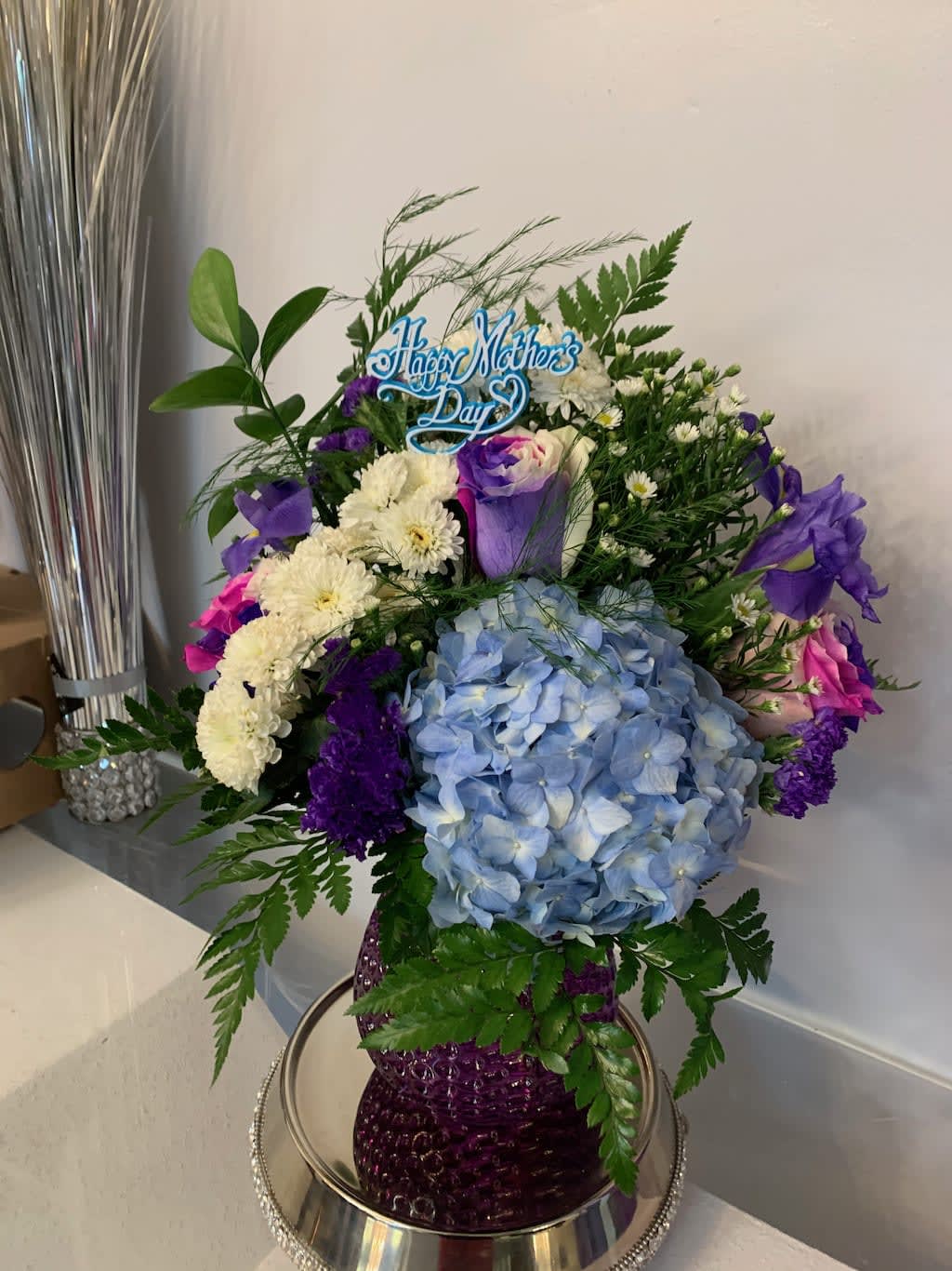 Blue hydrangea bouquet with purple and white flowers in a purple vase