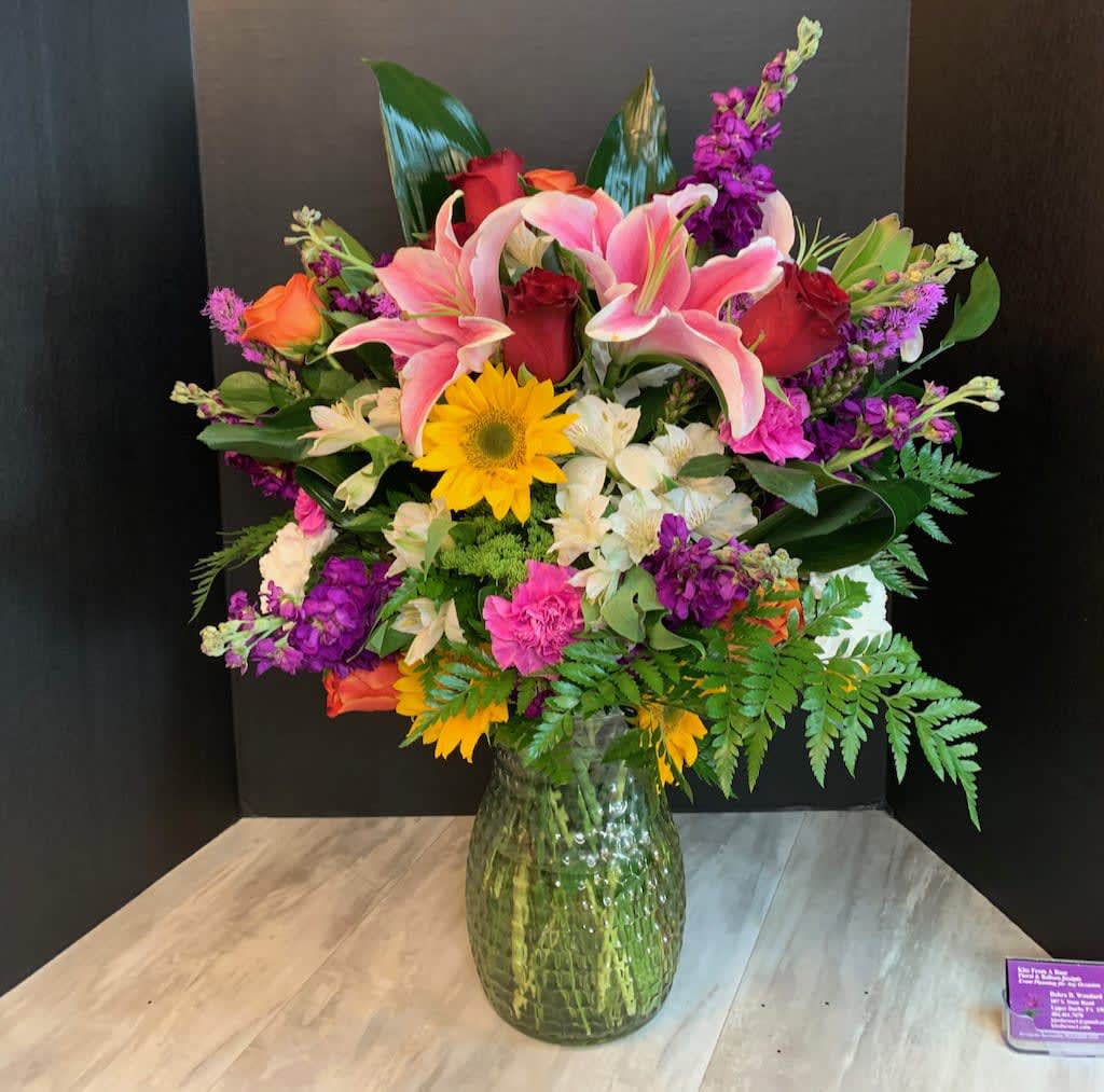 Mixed bouquet of lilies, roses, and daisies in a glass vase