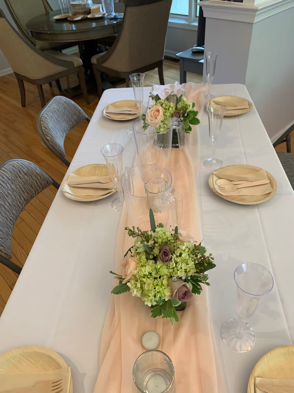 Low floral centerpieces on a set dining table with blush and green blooms