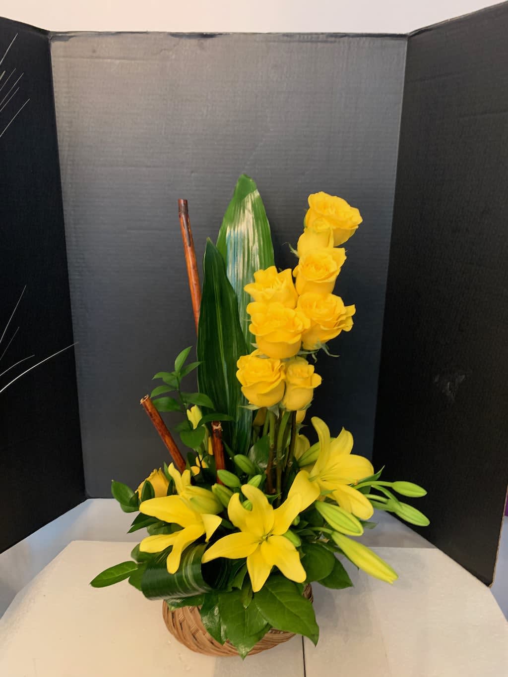 Yellow roses and lilies arranged in a basket