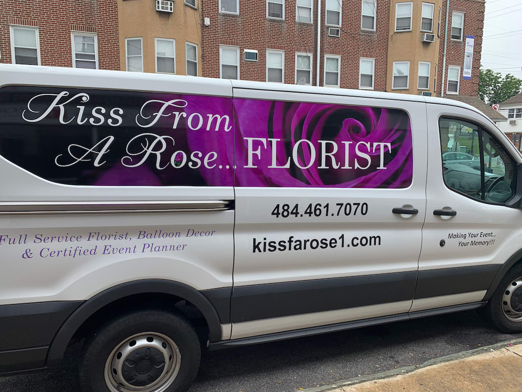 Branded florist van with a purple rose graphic and business text