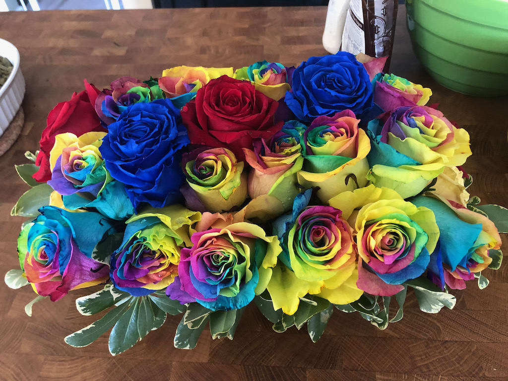 Bouquet of rainbow-colored roses with variegated greenery