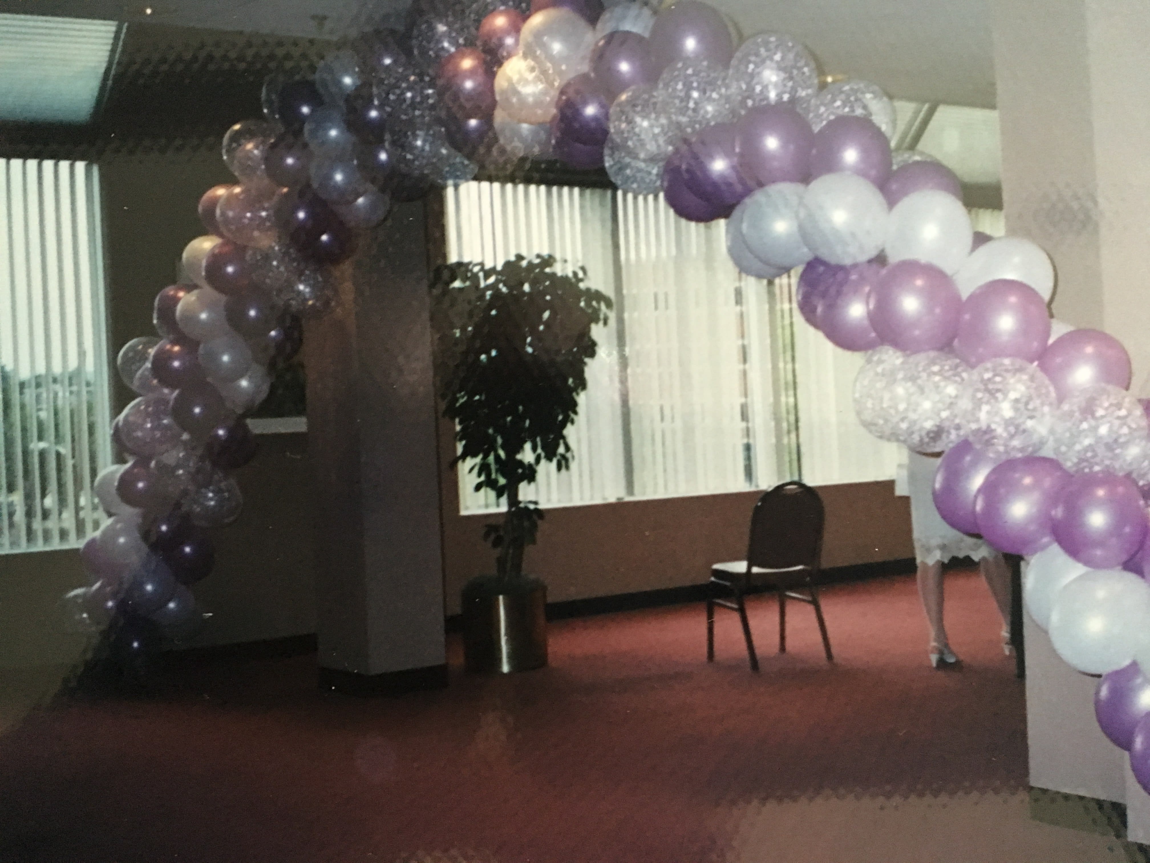 Purple and white balloon arch in an indoor room