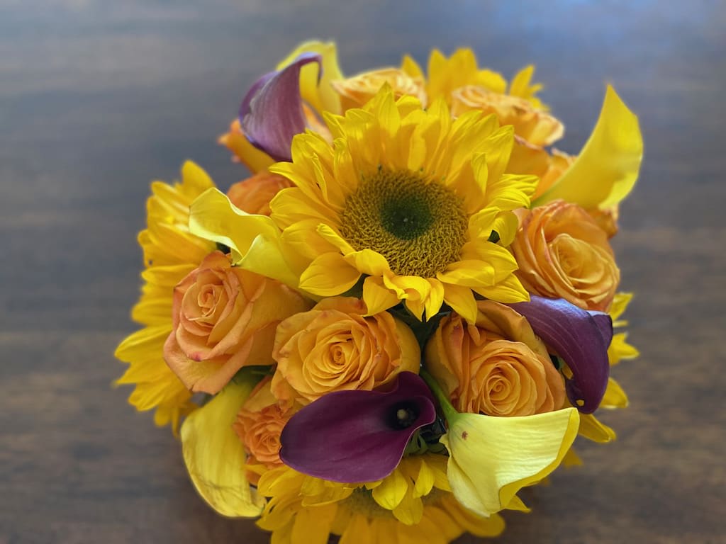 Bouquet of sunflowers, orange roses, and purple calla lilies