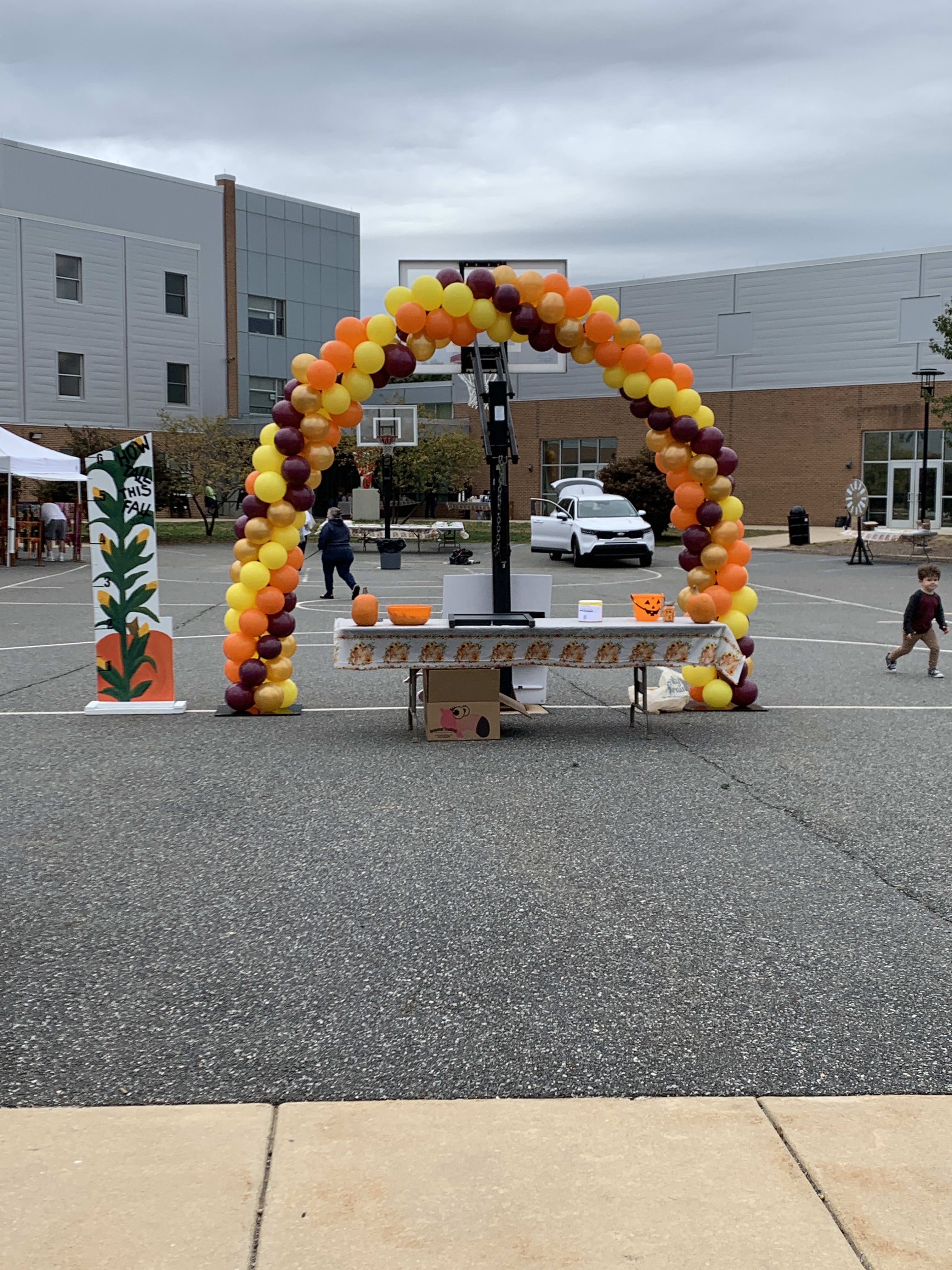 Balloon arch in yellow, orange, and burgundy at an outdoor event