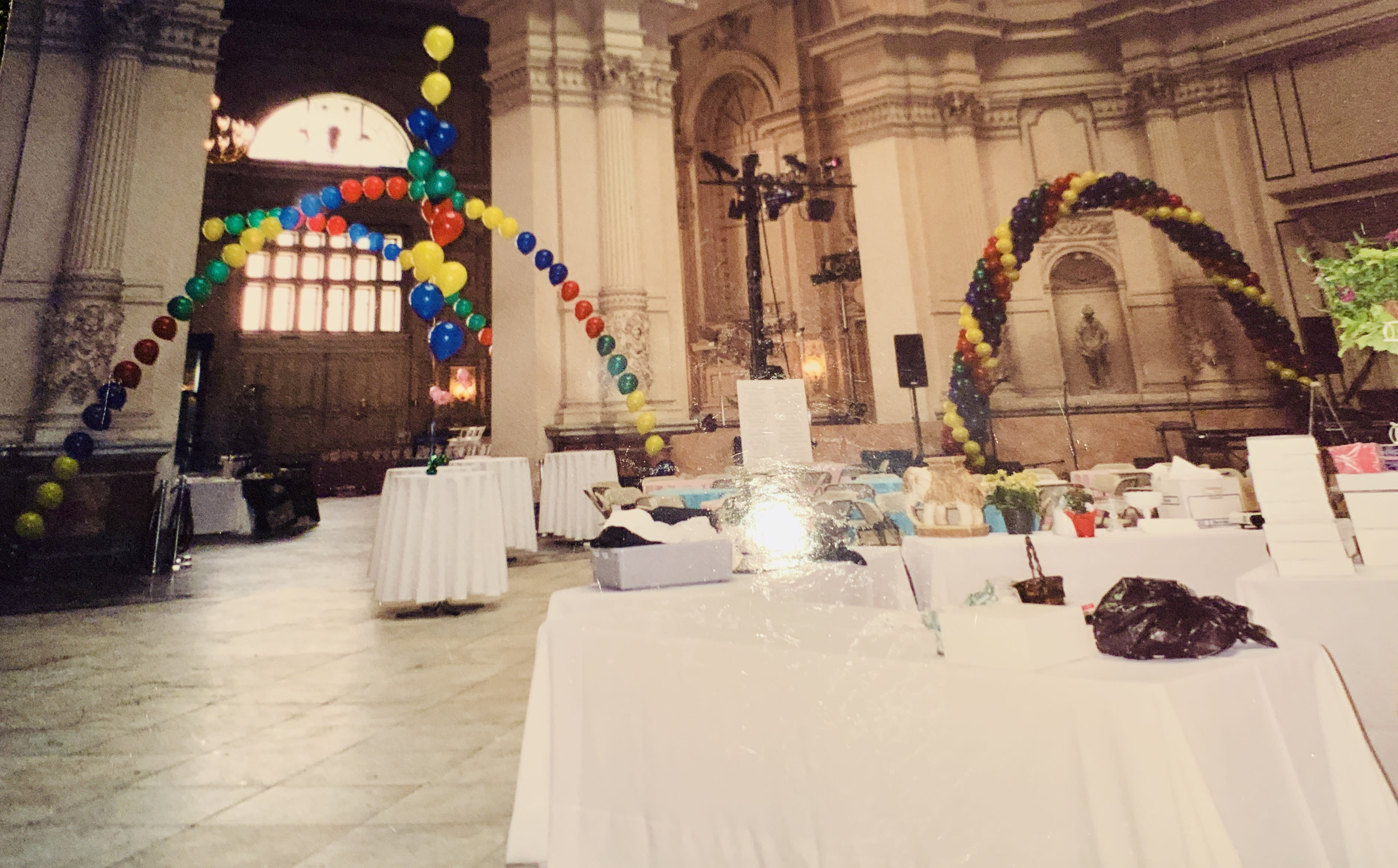Colorful balloon arches in a large hall with tables below