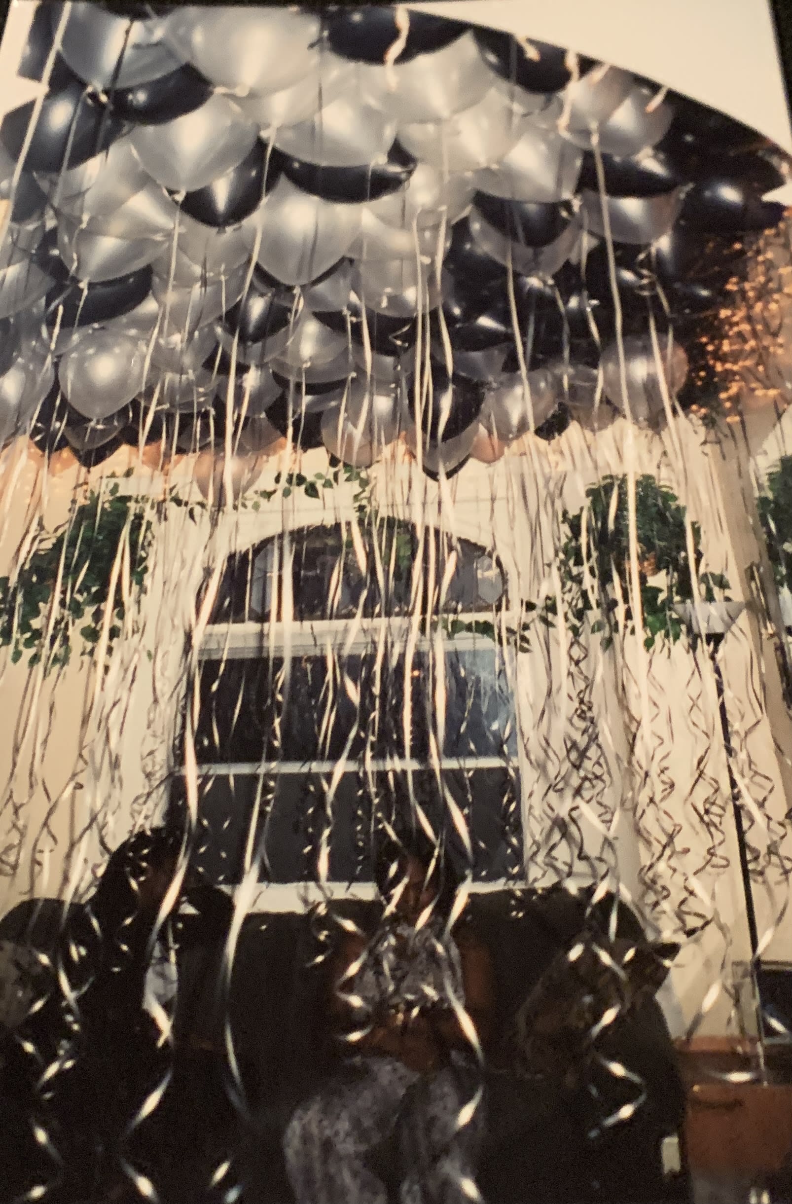Cluster of black and silver balloons with long hanging ribbons