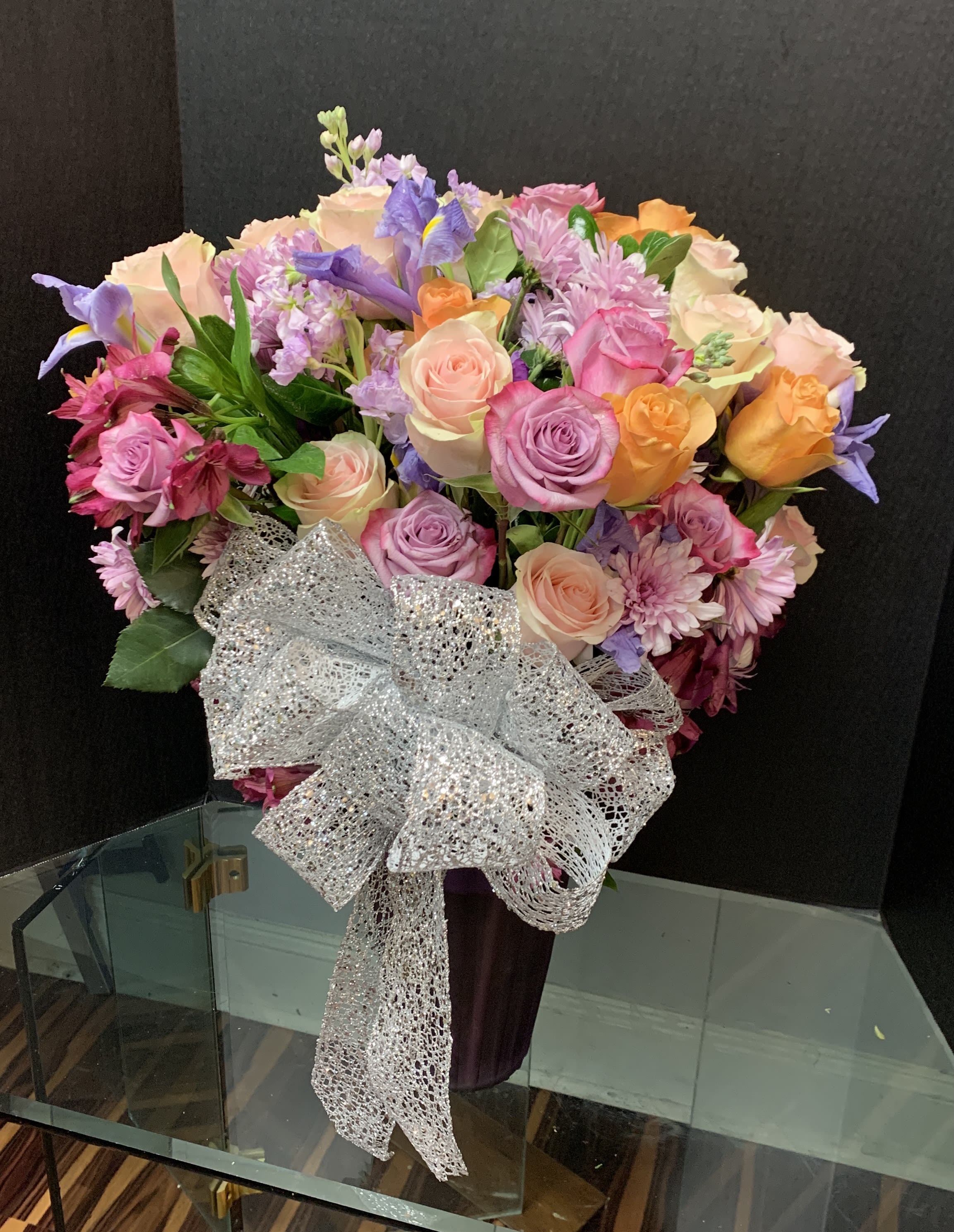 Mixed bouquet of pastel roses, irises, and chrysanthemums with a silver bow
