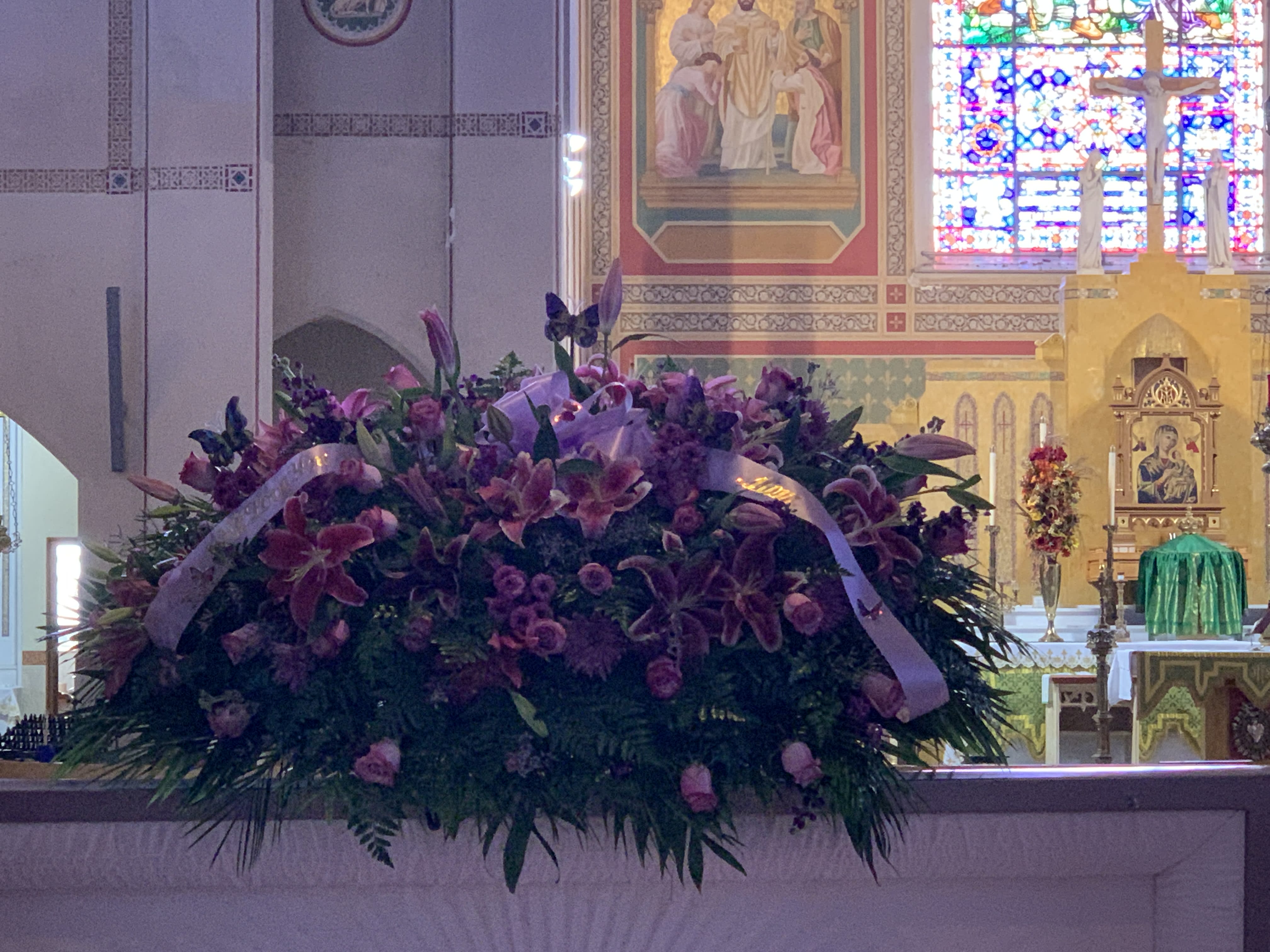 Large purple floral arrangement with ribbon in a church