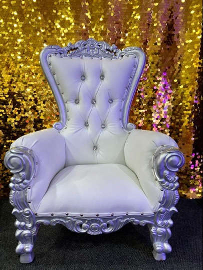 Ornate white tufted throne chair in front of a gold sequin backdrop