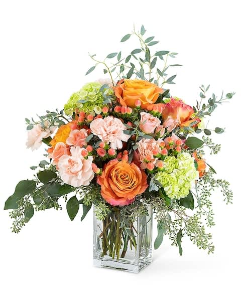 Orange and peach roses with hydrangeas in a clear glass vase