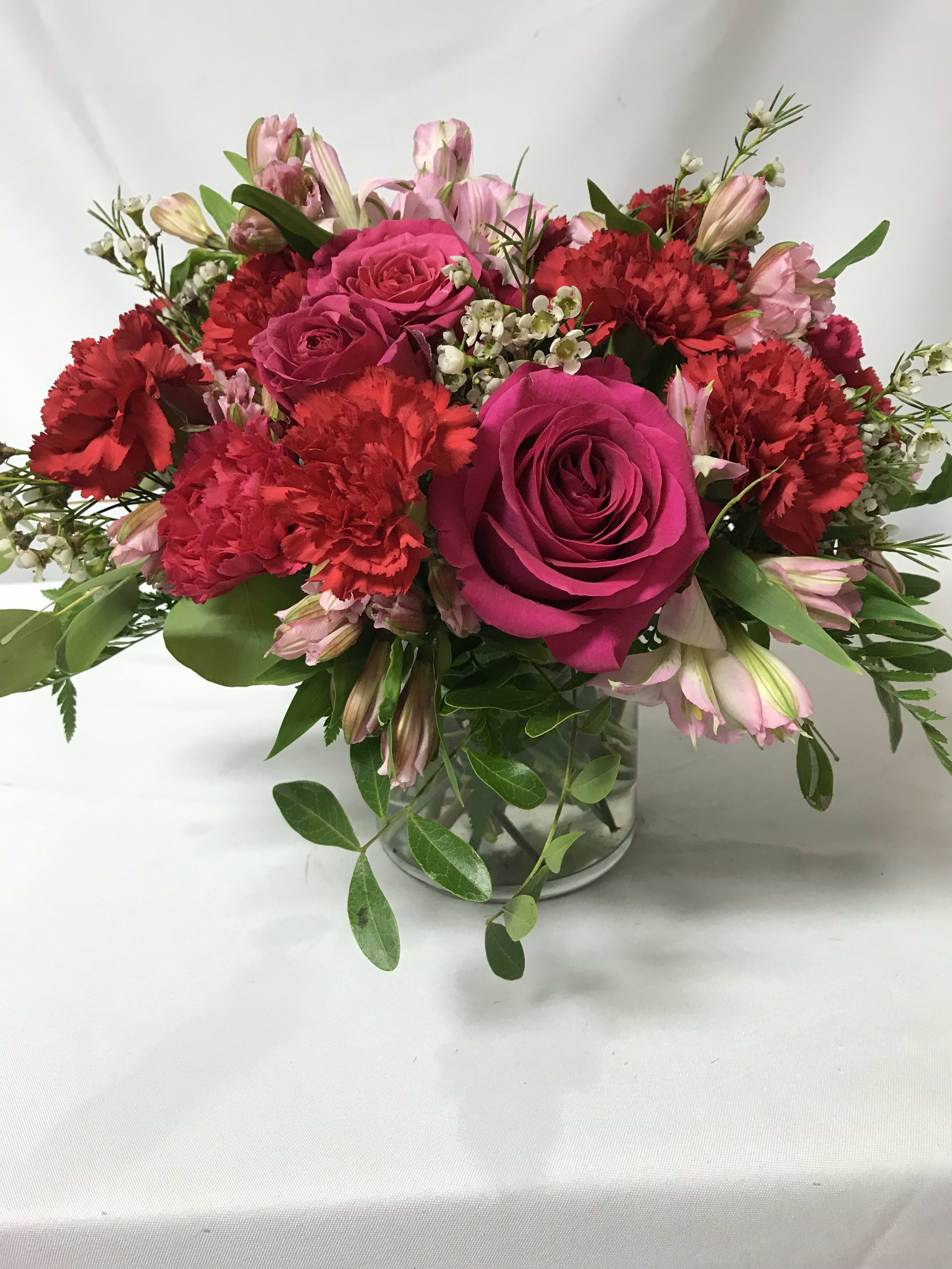 Bouquet of pink roses and red carnations in a glass vase