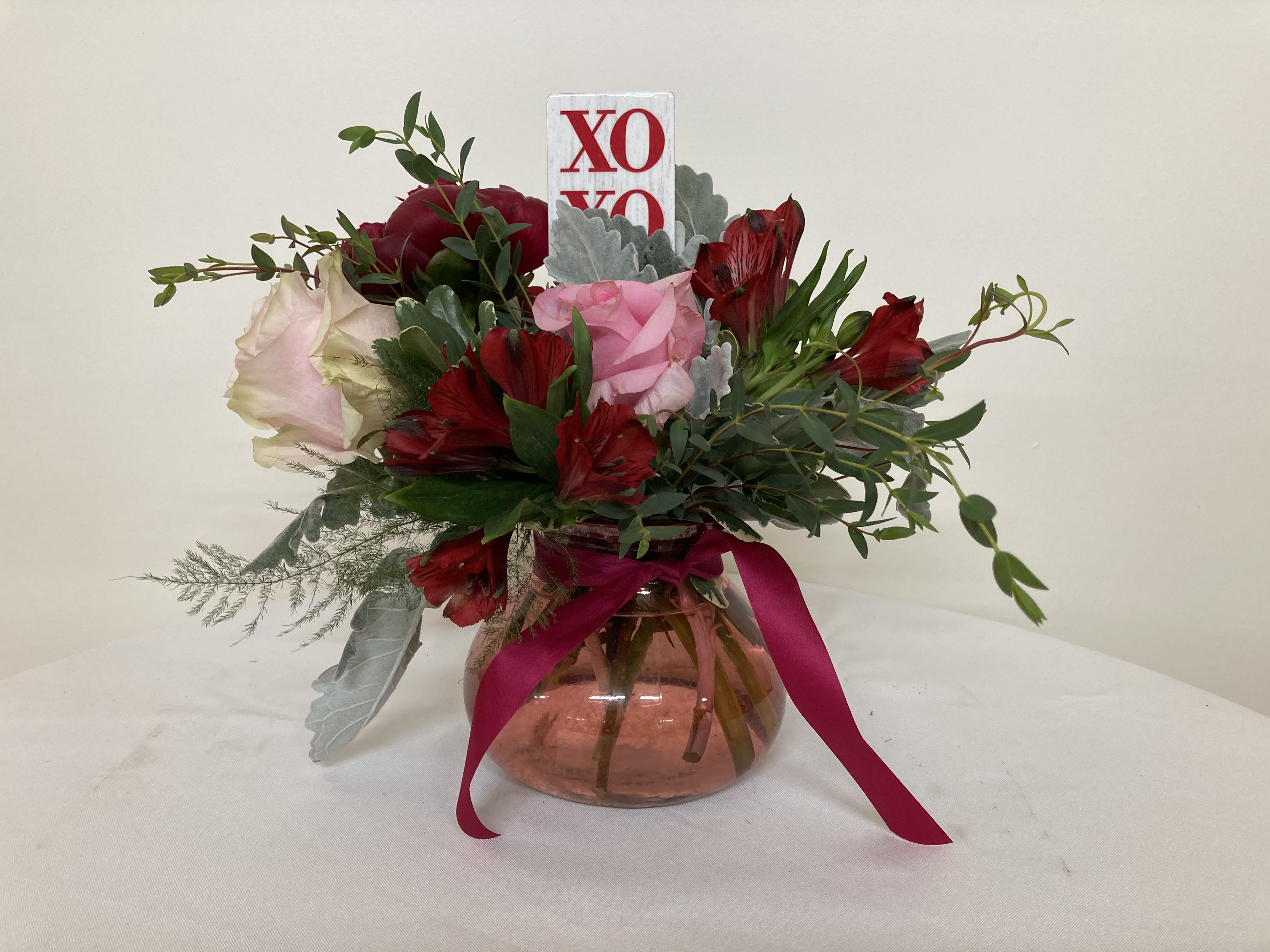 Bouquet of red and pink flowers in a glass vase with a ribbon