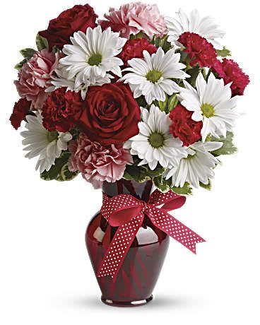 Red and white mixed bouquet in a red vase with a polka-dot ribbon