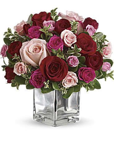Bouquet of red, pink, and blush roses in a clear square vase