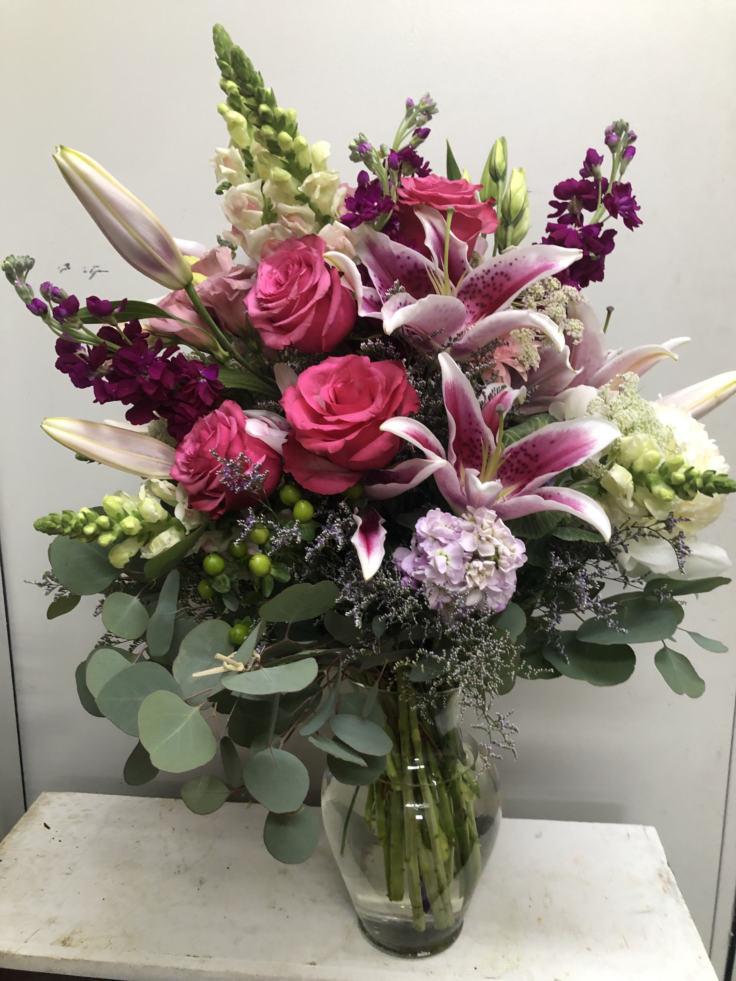Pink roses and lilies arranged in a clear glass vase