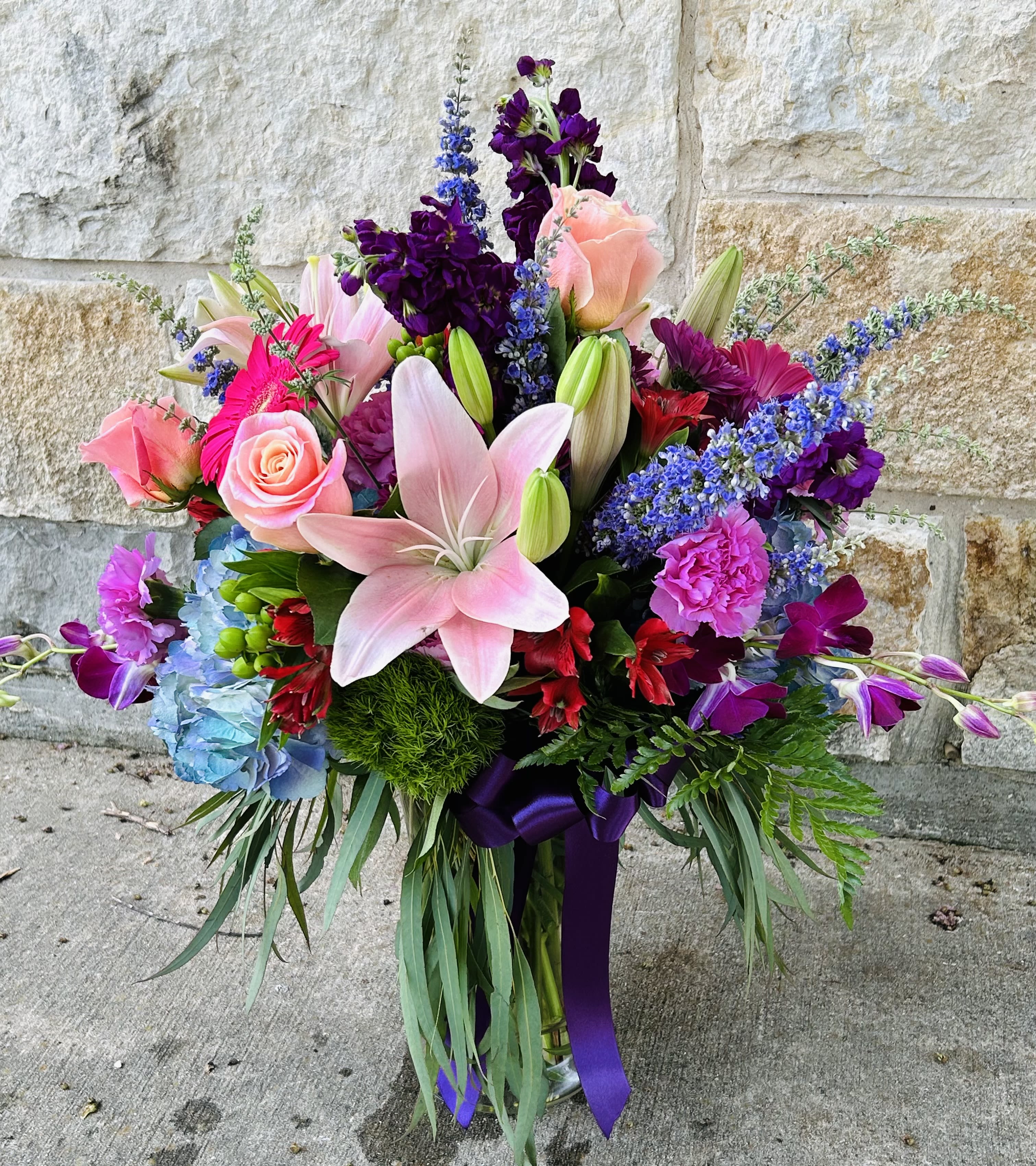 Colorful bouquet with pink lilies, roses, and purple flowers in a vase