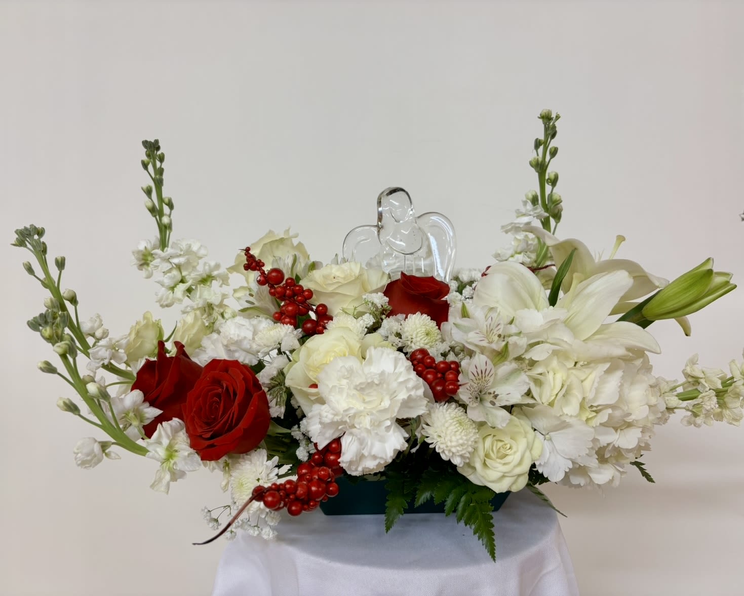 Red and white floral arrangement with a clear angel figurine