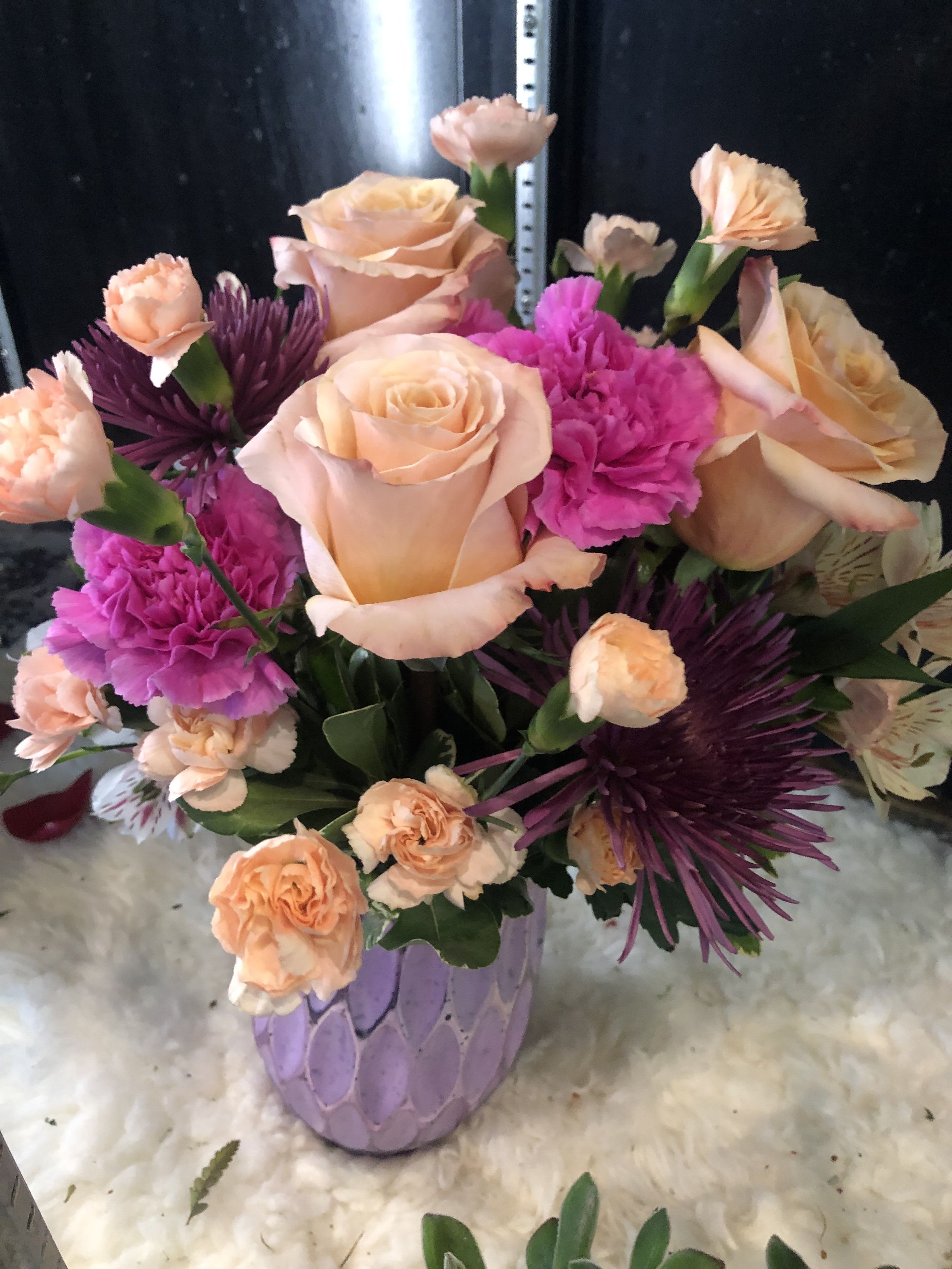 Peach roses and pink carnations in a lavender vase