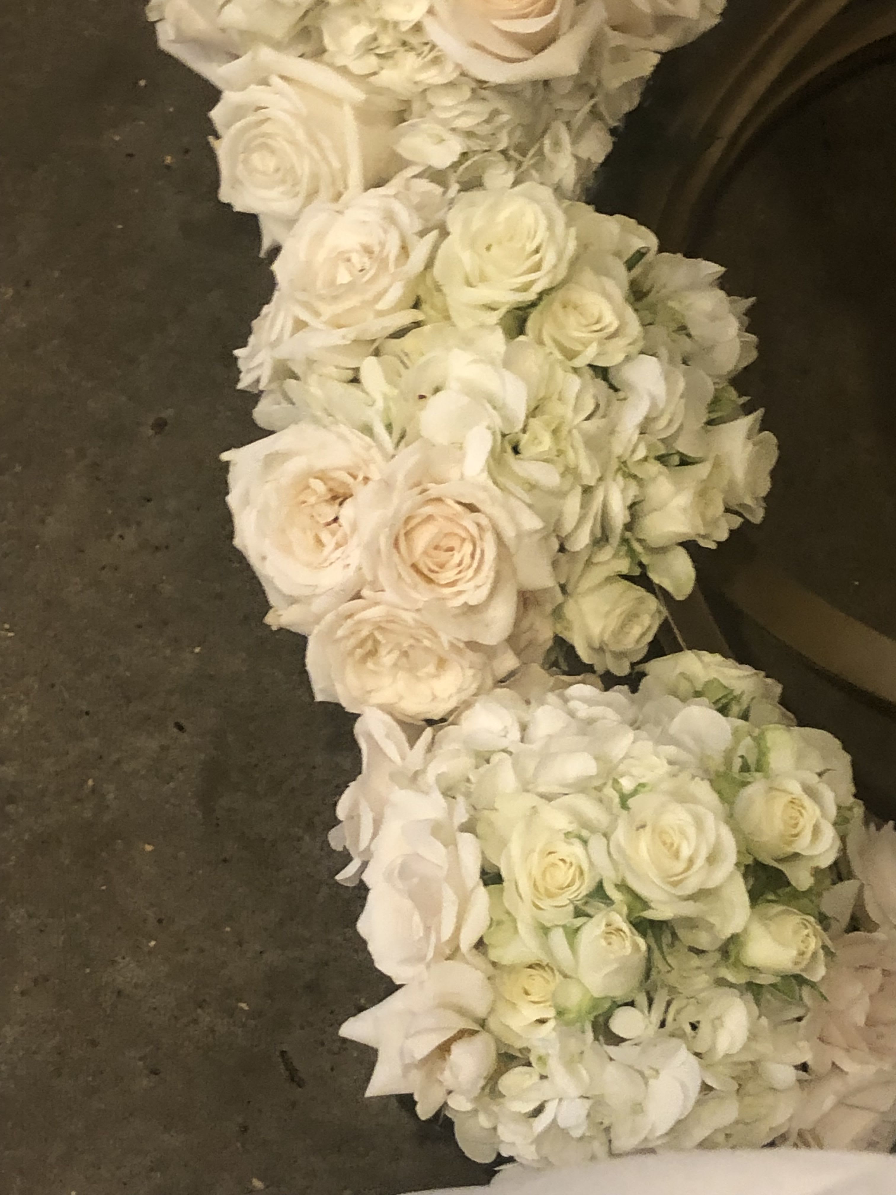 White rose and hydrangea floral garland on a dark surface