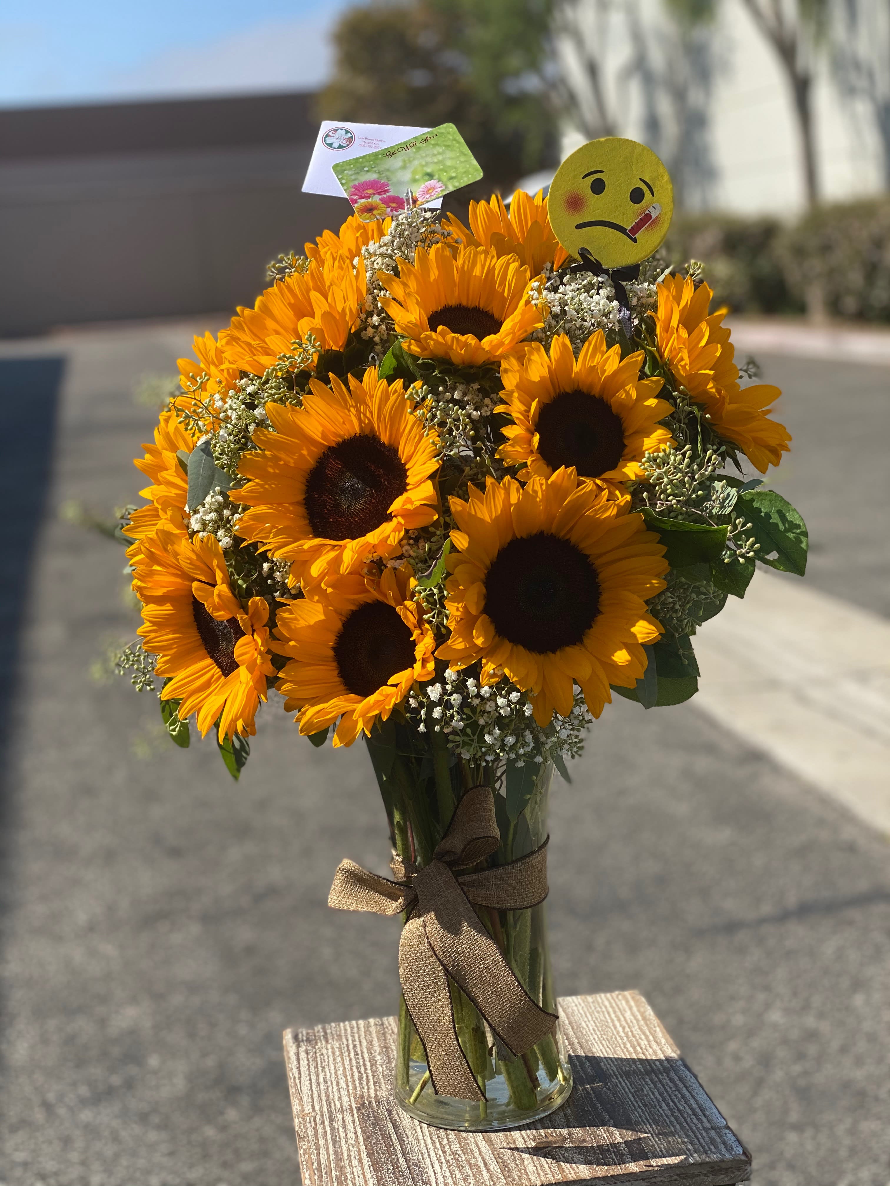 Bouquet of sunflowers in a glass vase with a ribbon and emoji pick