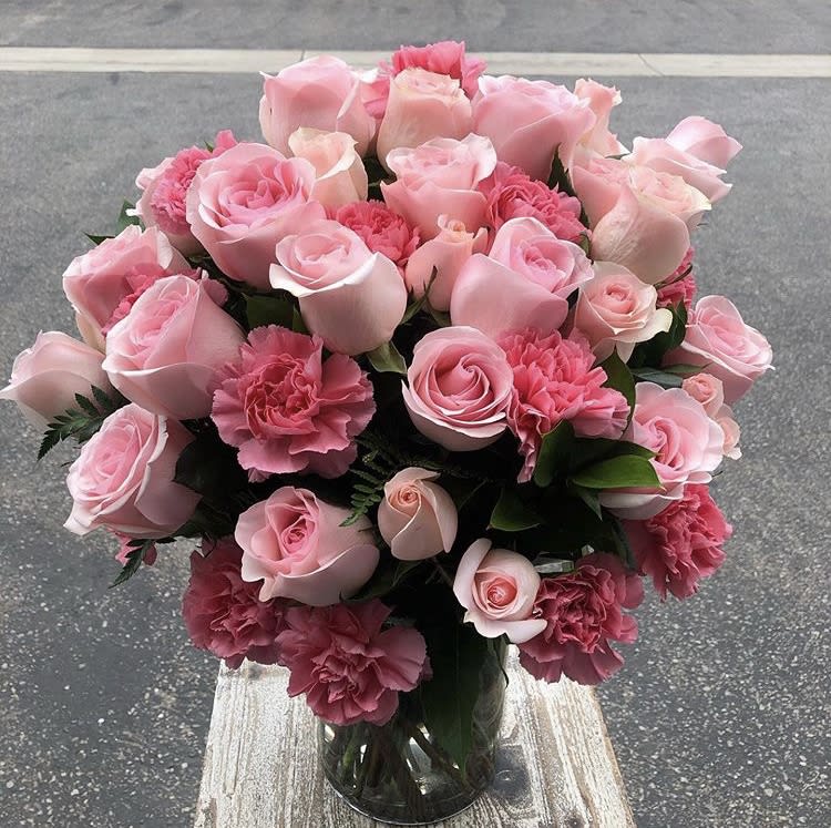 Pink roses and carnations arranged in a clear glass vase