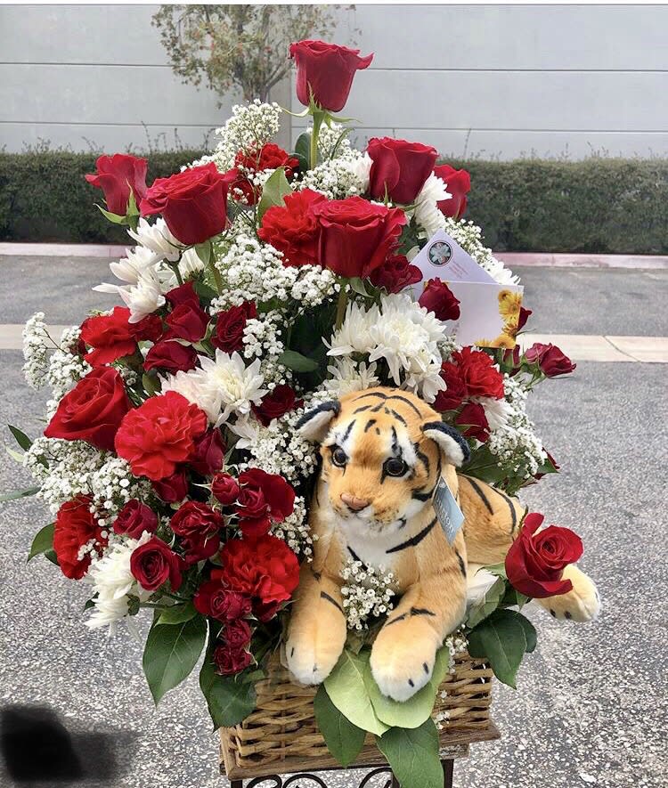 Basket arrangement of red roses, white daisies, and a plush tiger