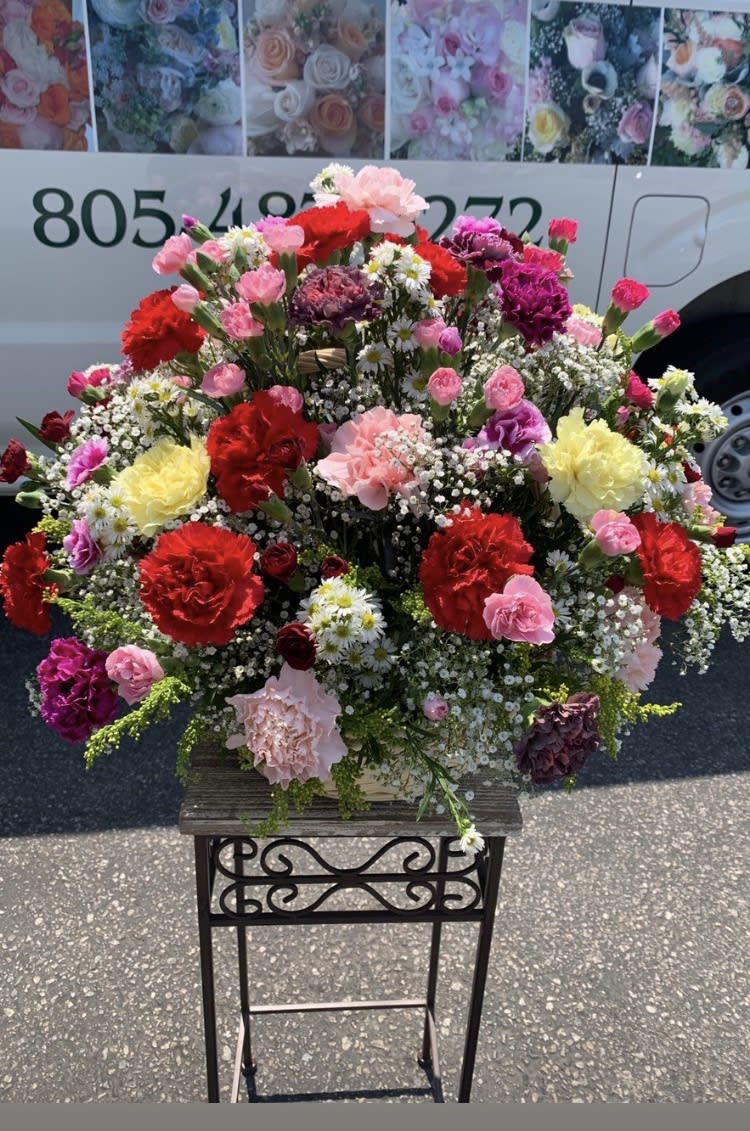 Large mixed flower arrangement in a basket on a stand
