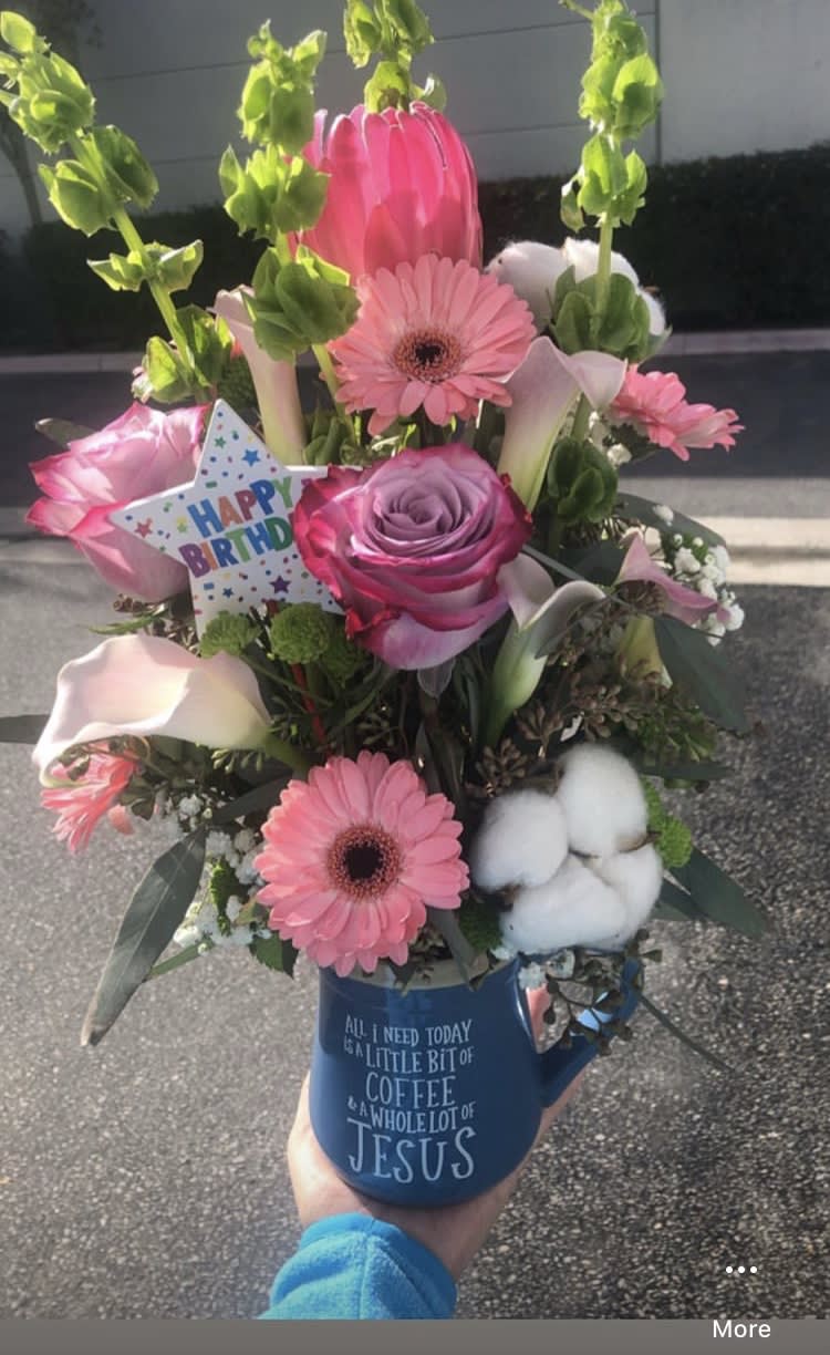 Pink mixed flower bouquet in a blue mug with a birthday card.