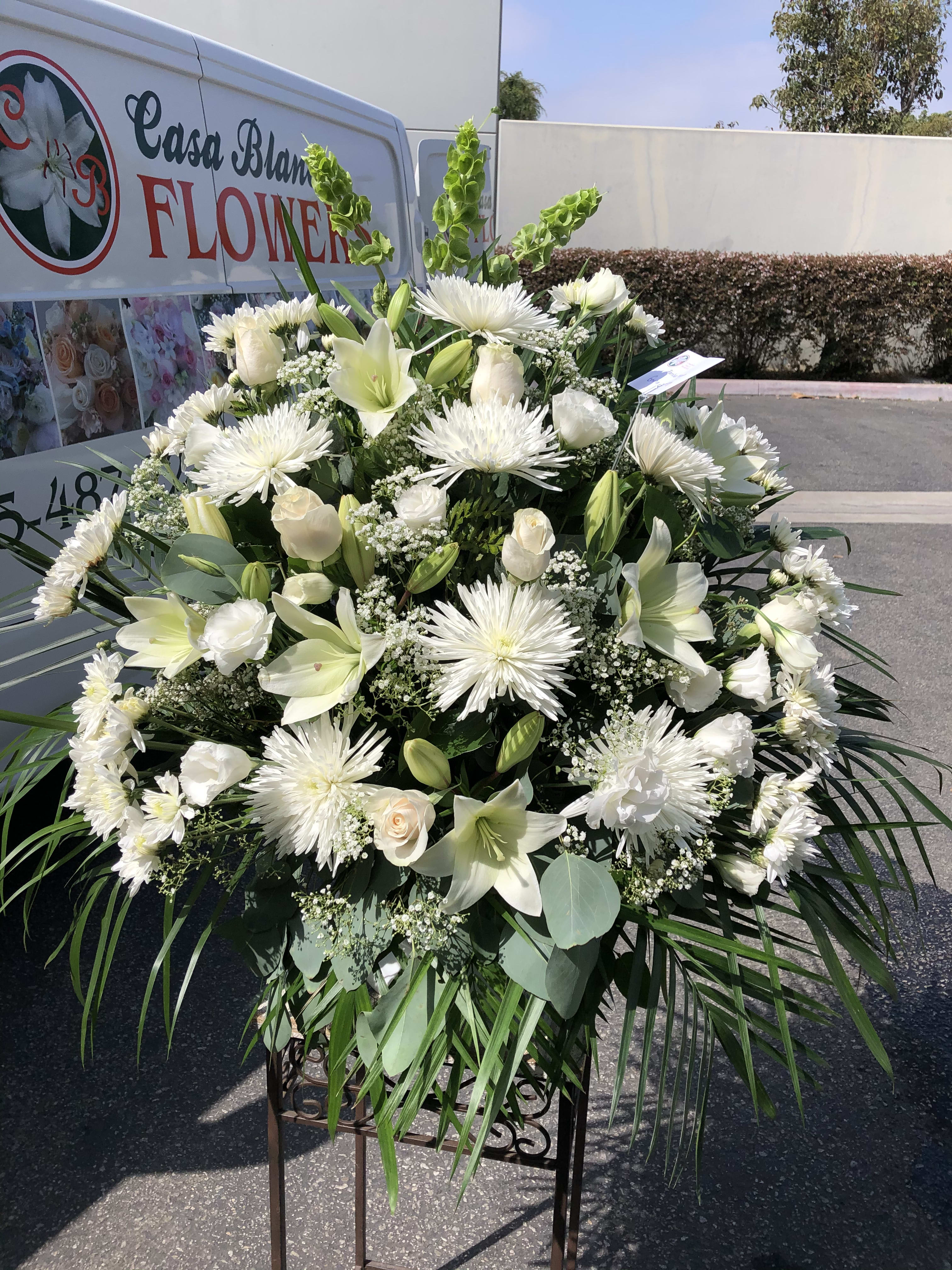 Large white funeral spray with lilies, roses, and spider mums