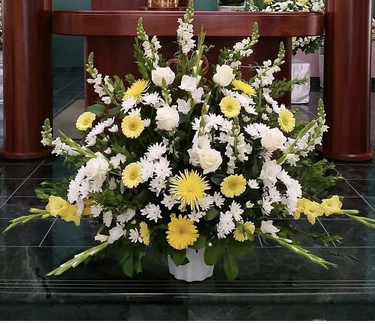 Large white and yellow floral arrangement in a white container