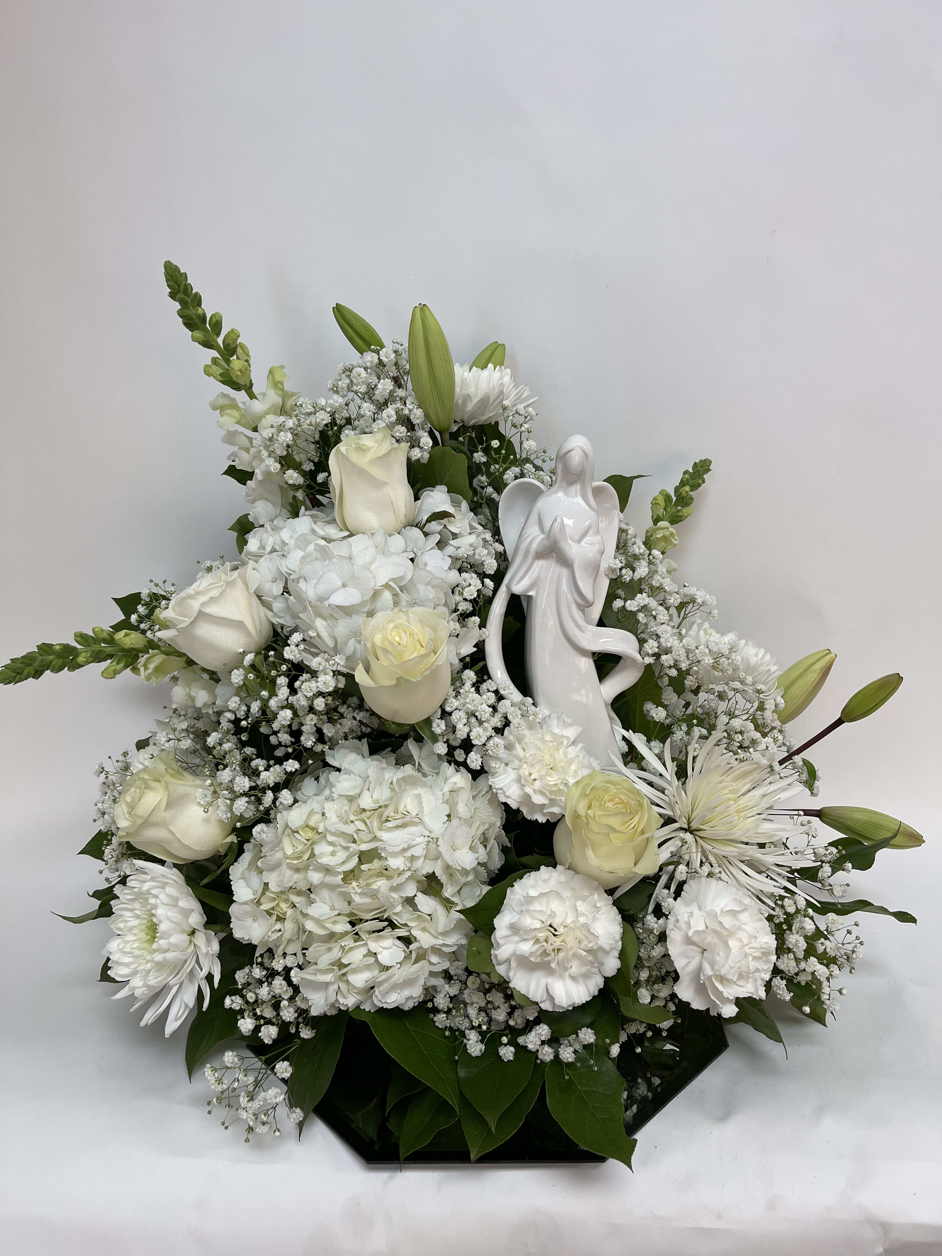 White floral arrangement with roses, lilies, and an angel figurine