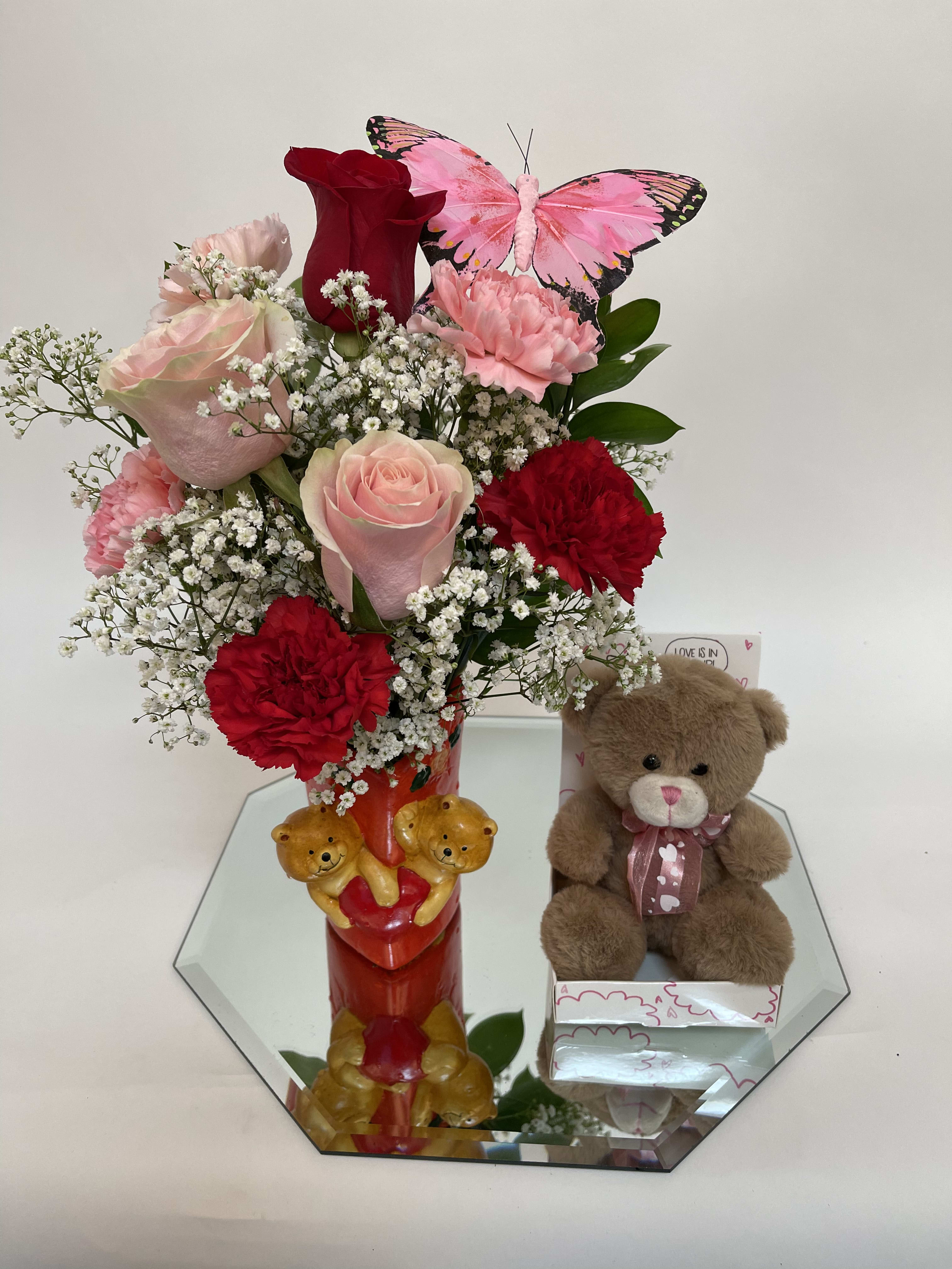 Pink and red flower arrangement with a teddy bear and butterfly