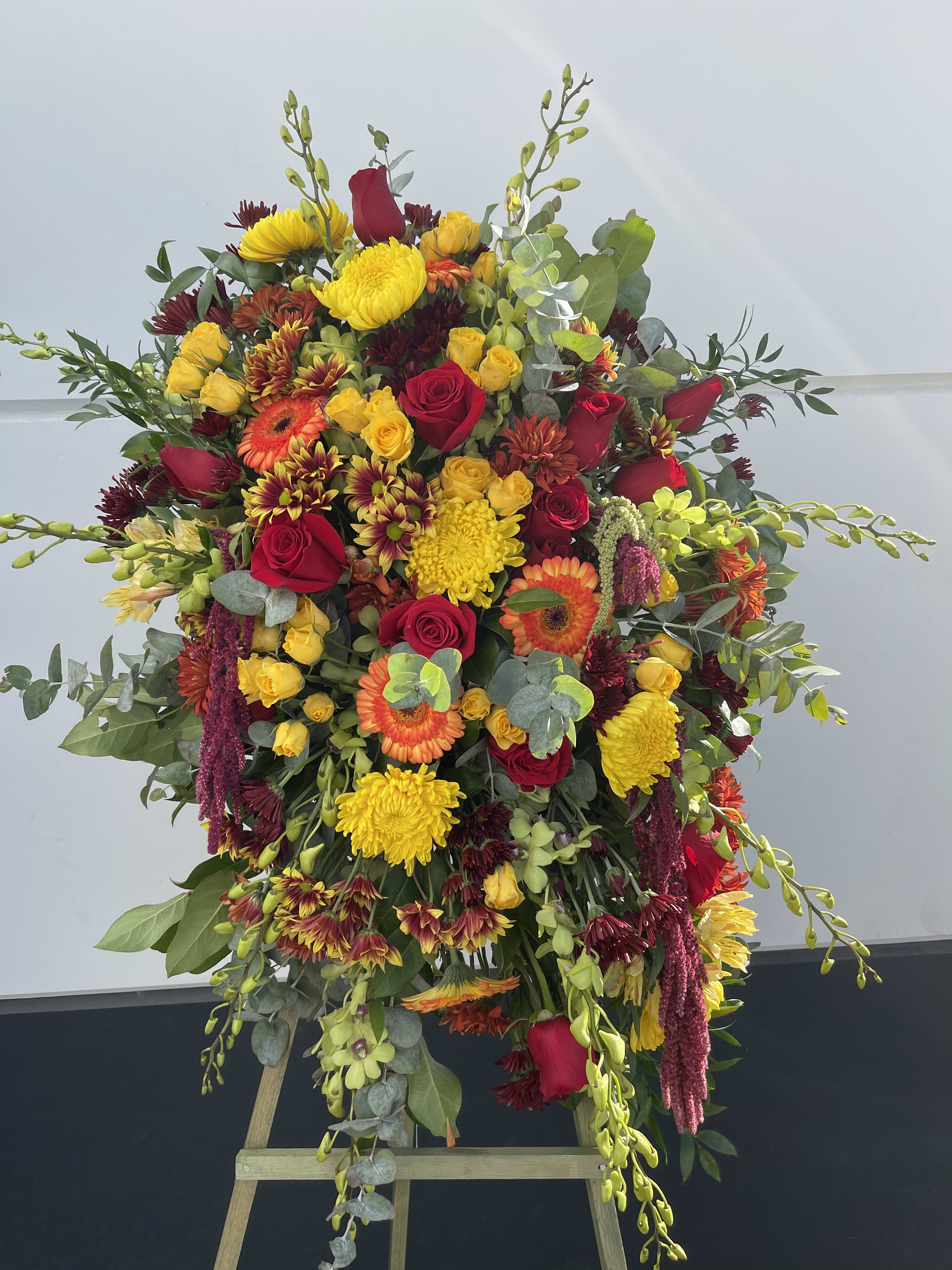 Large standing floral spray with red, yellow, and orange blooms on an easel