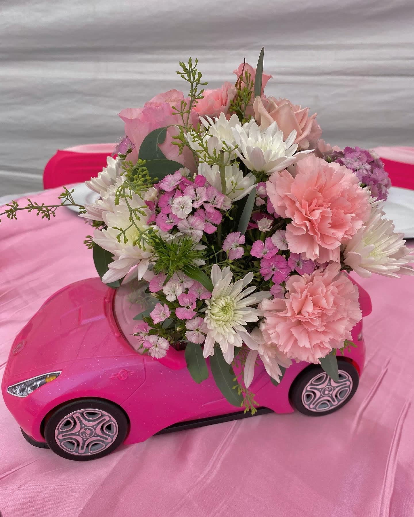 Pink and white bouquet arranged in a pink toy car