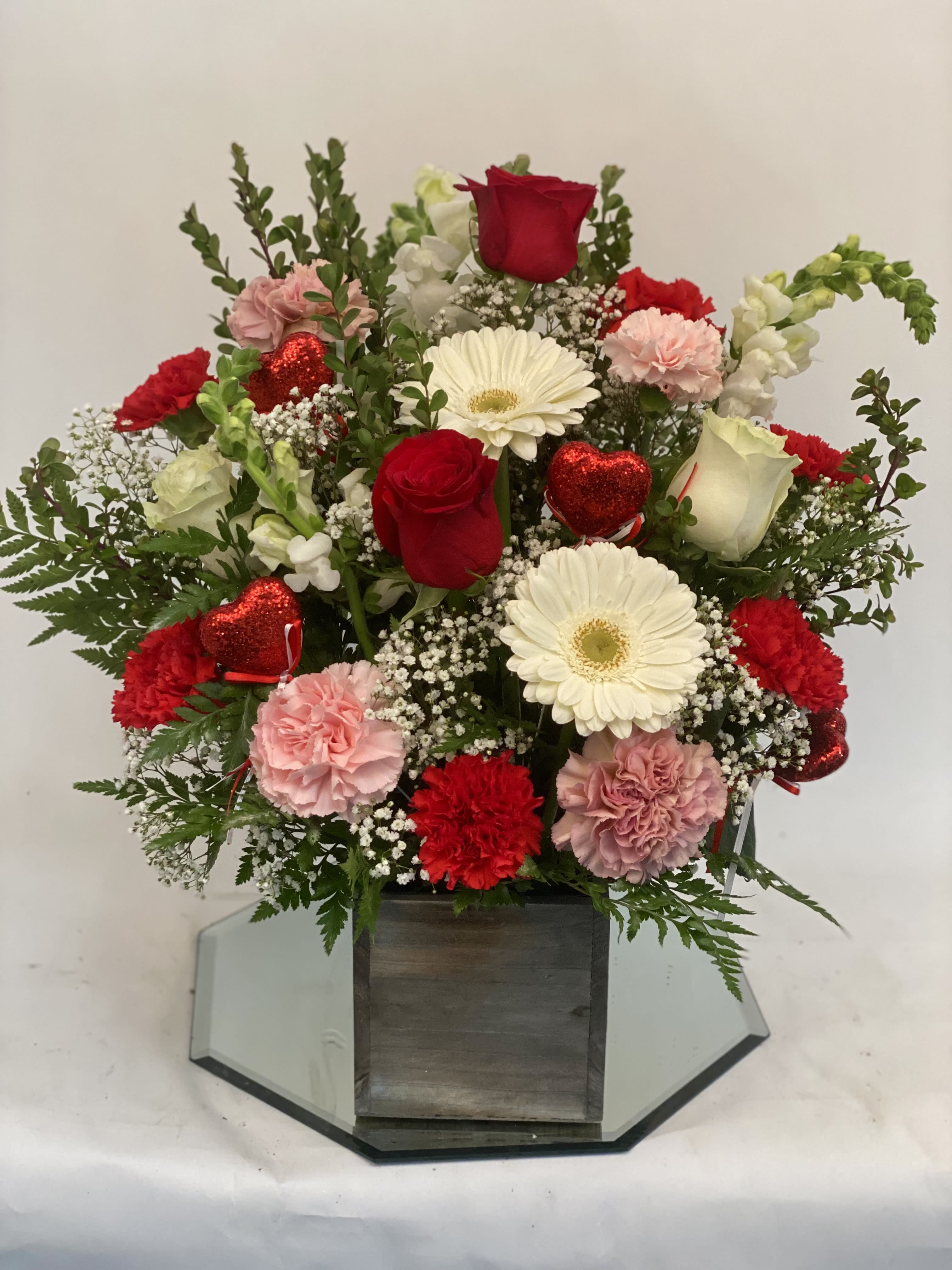 Mixed bouquet of red and white flowers in a wooden box with red heart picks