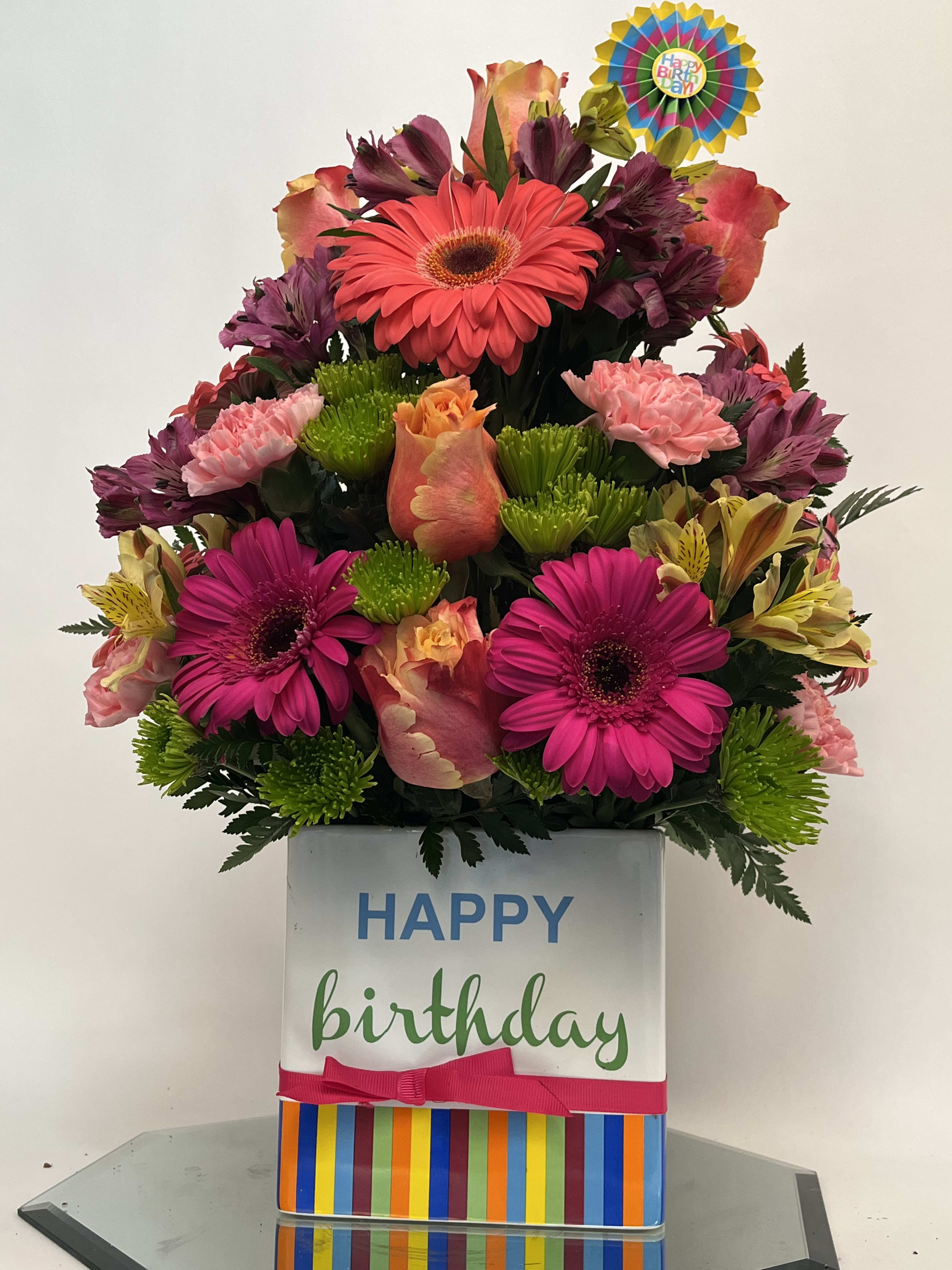 Birthday flower arrangement in a striped gift box with a "Happy Birthday" topper