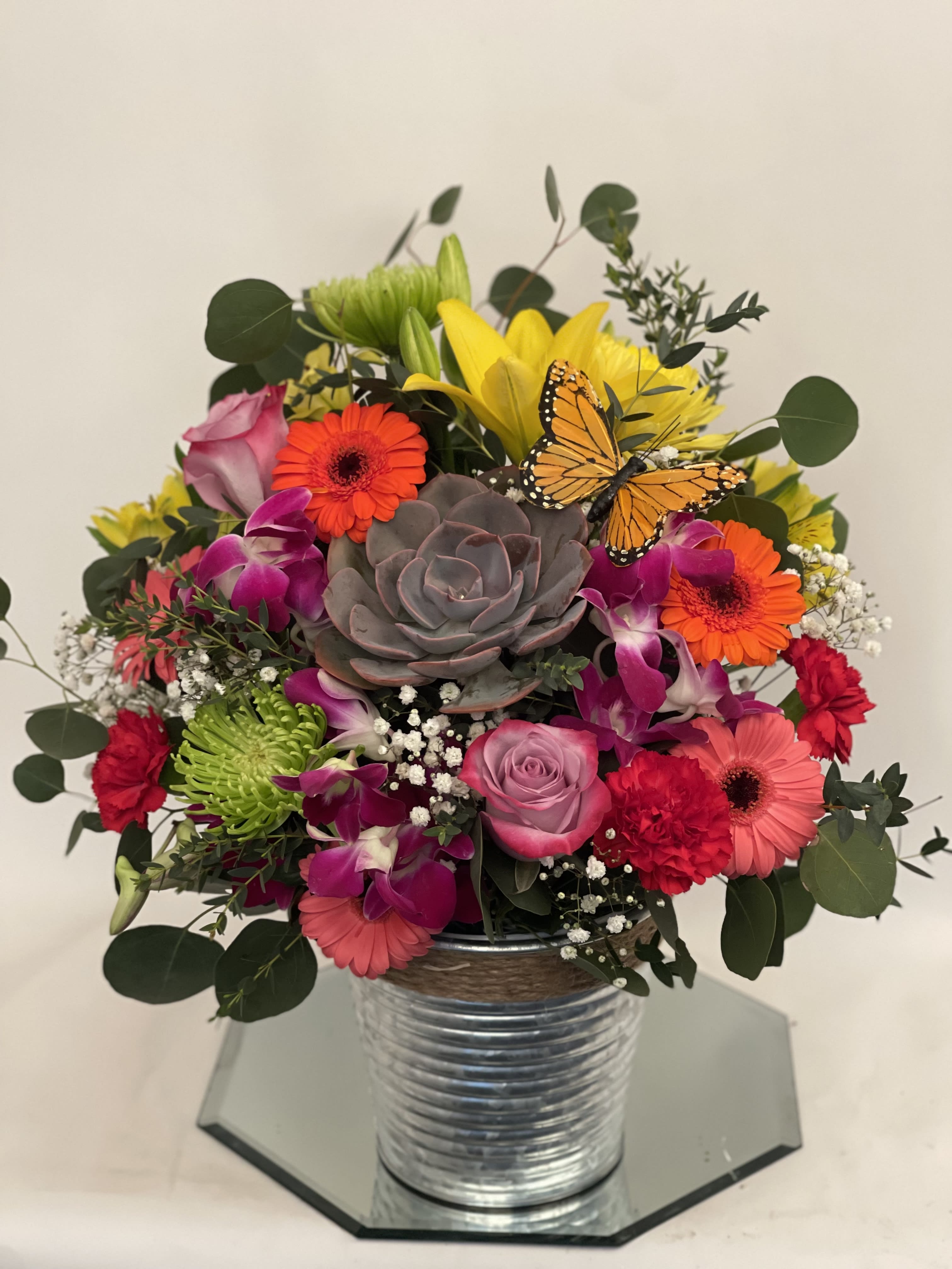 Mixed bouquet in a metal vase with a butterfly accent