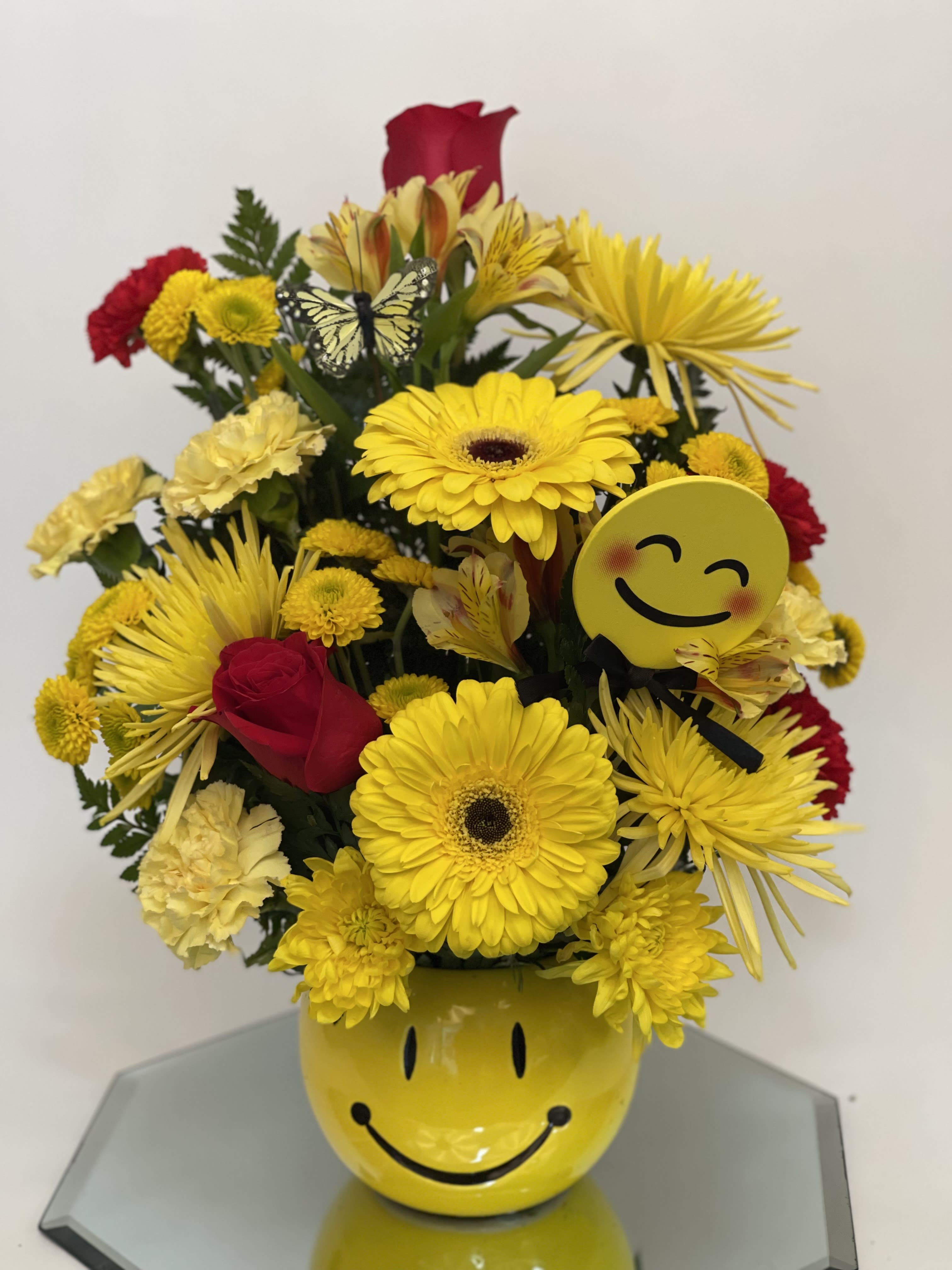 Yellow and red mixed bouquet in a smiley-face vase with emoji accents