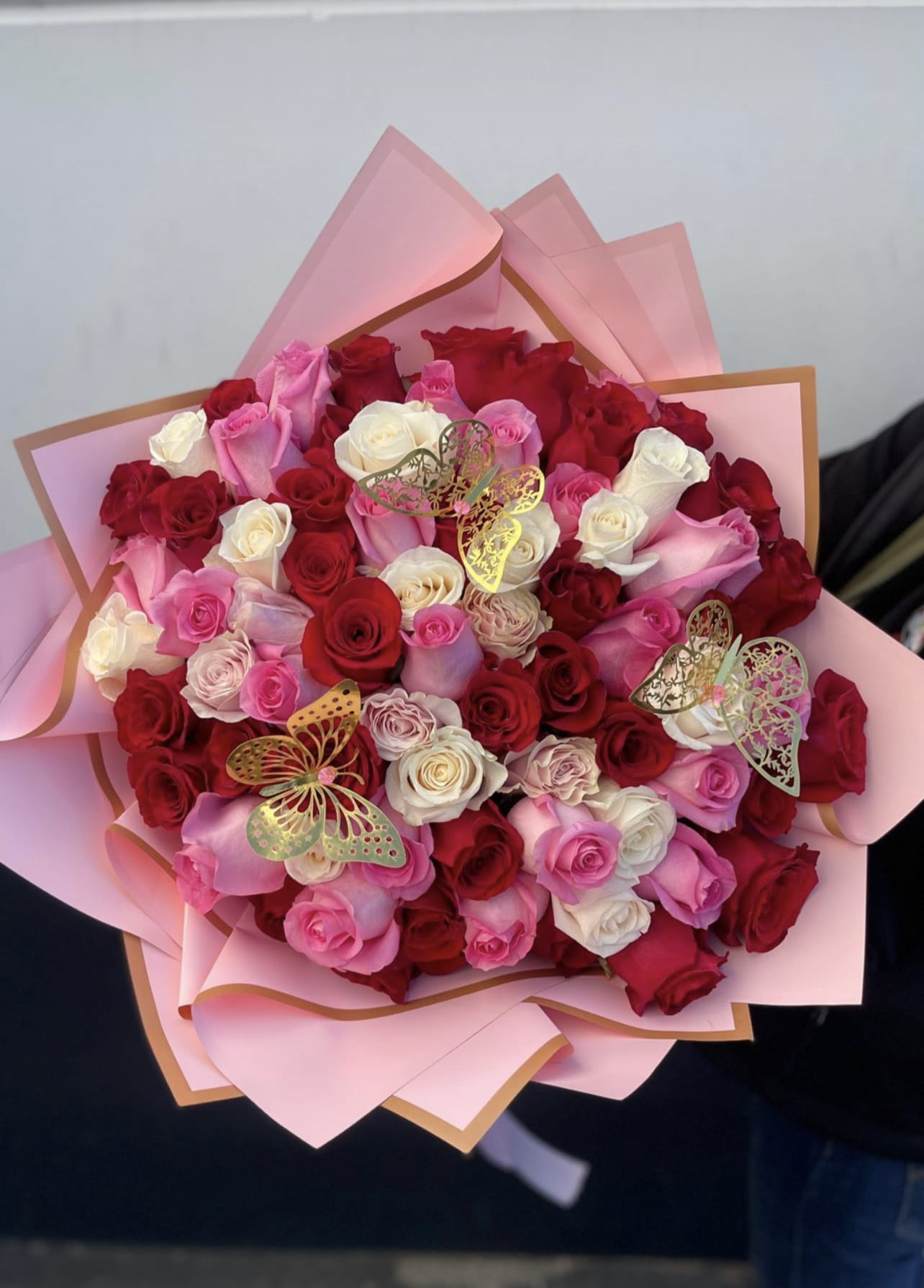 Bouquet of red, pink, and white roses wrapped in pink paper