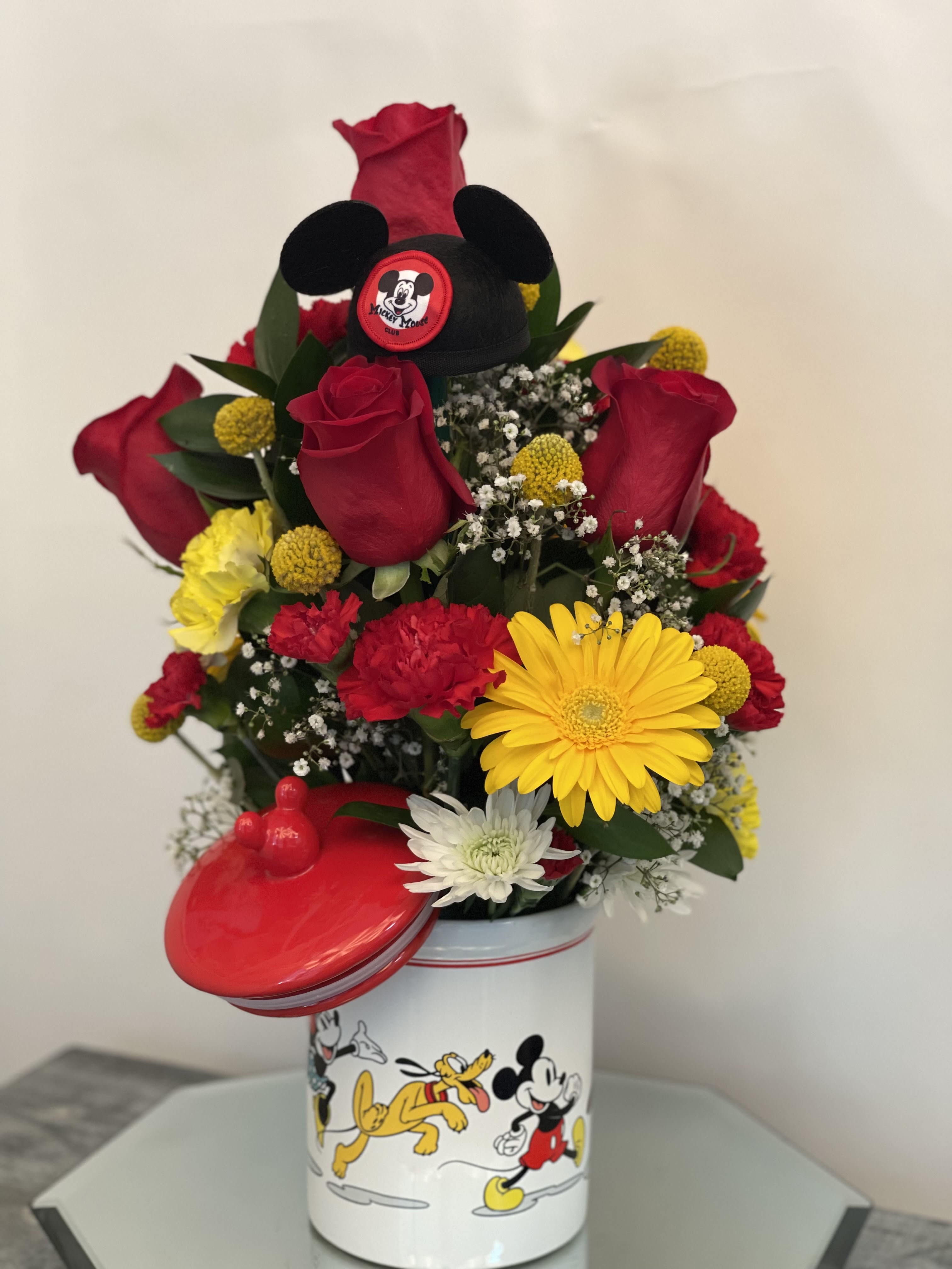 Bouquet of red roses and mixed flowers in a Mickey Mouse tin