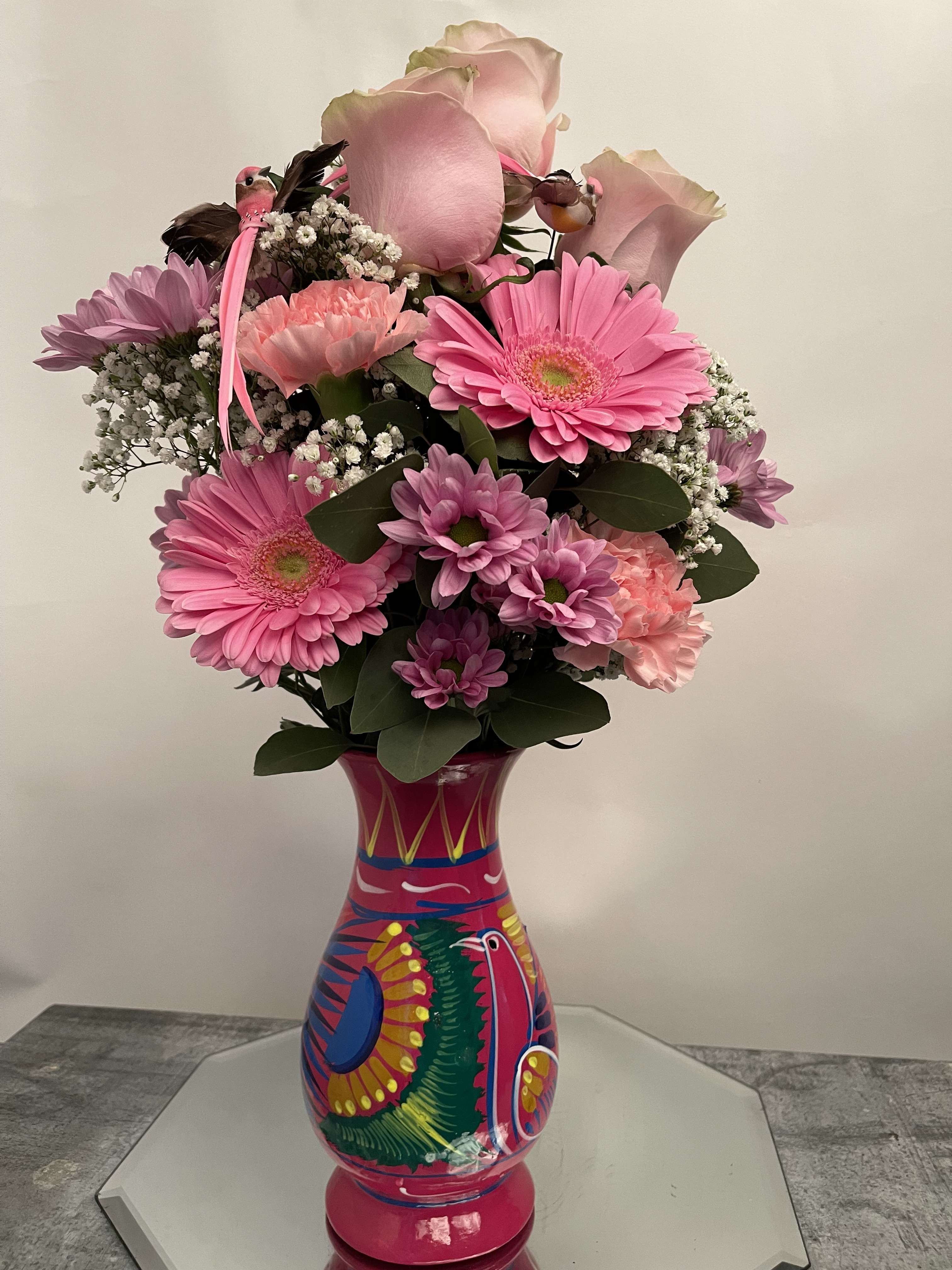 Pink and lavender flower arrangement in a colorful painted vase