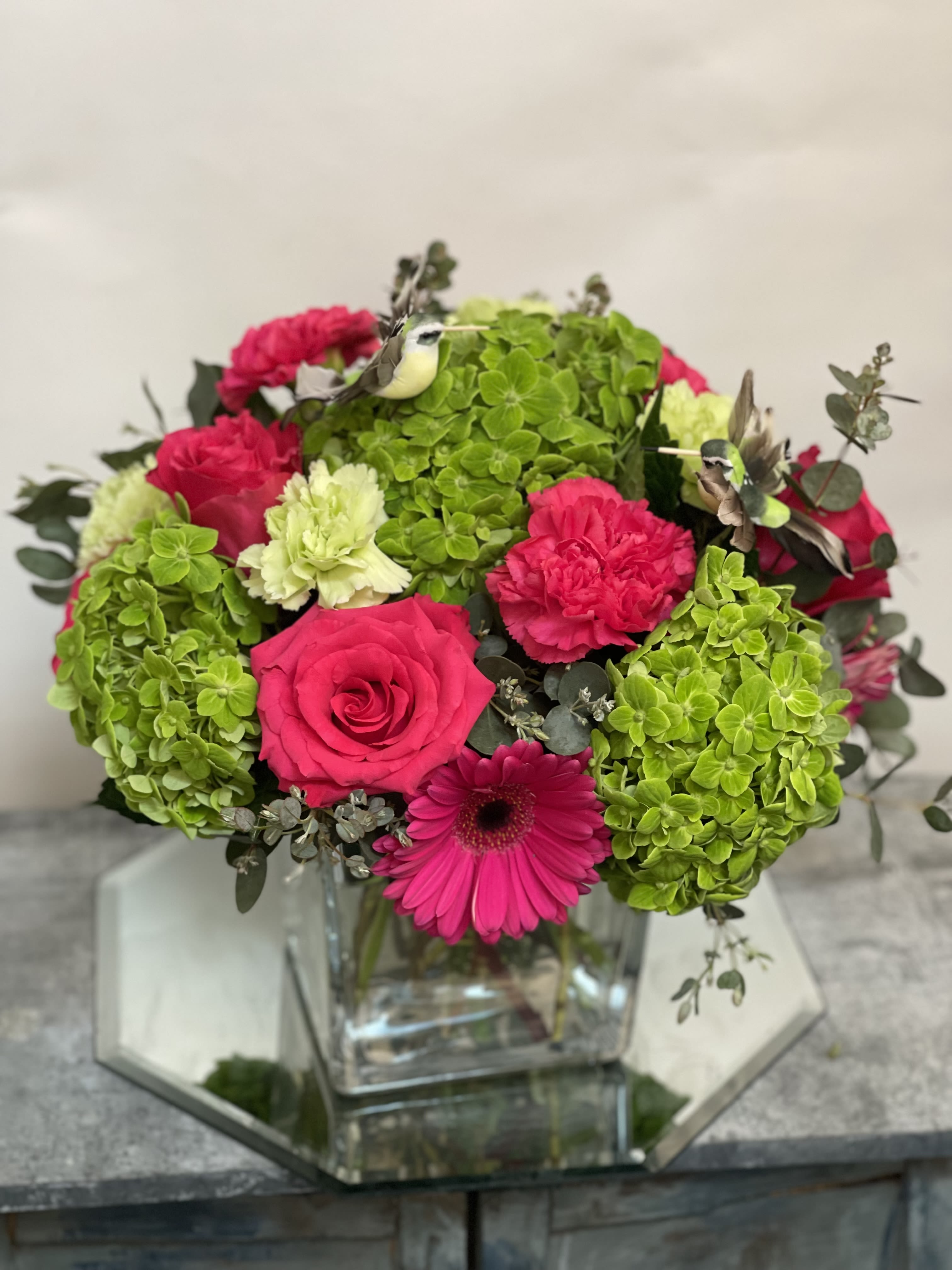 Pink roses and gerbera daisy in a glass vase with green hydrangea