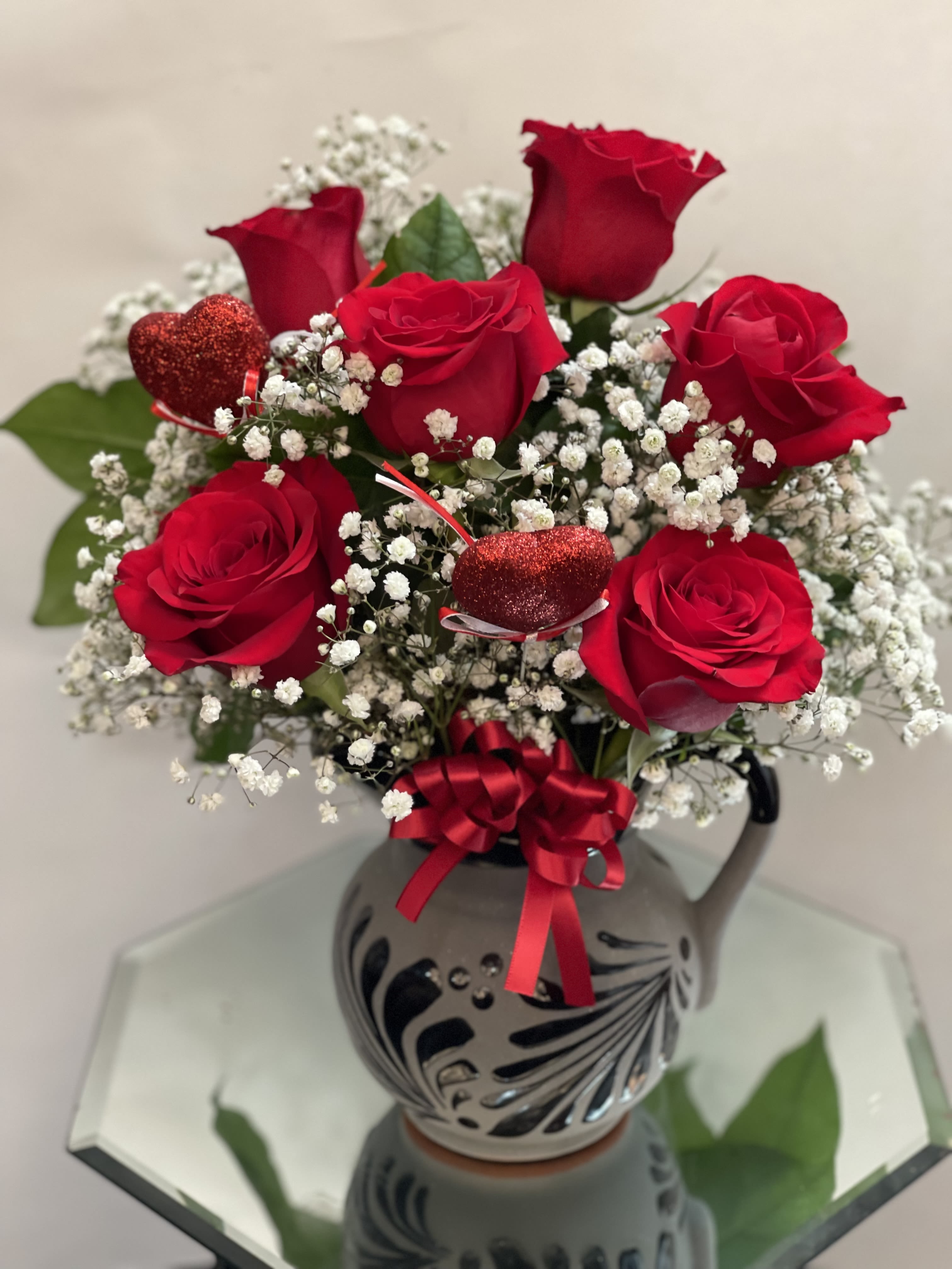 Red roses with baby's breath in a decorative vase and ribbon