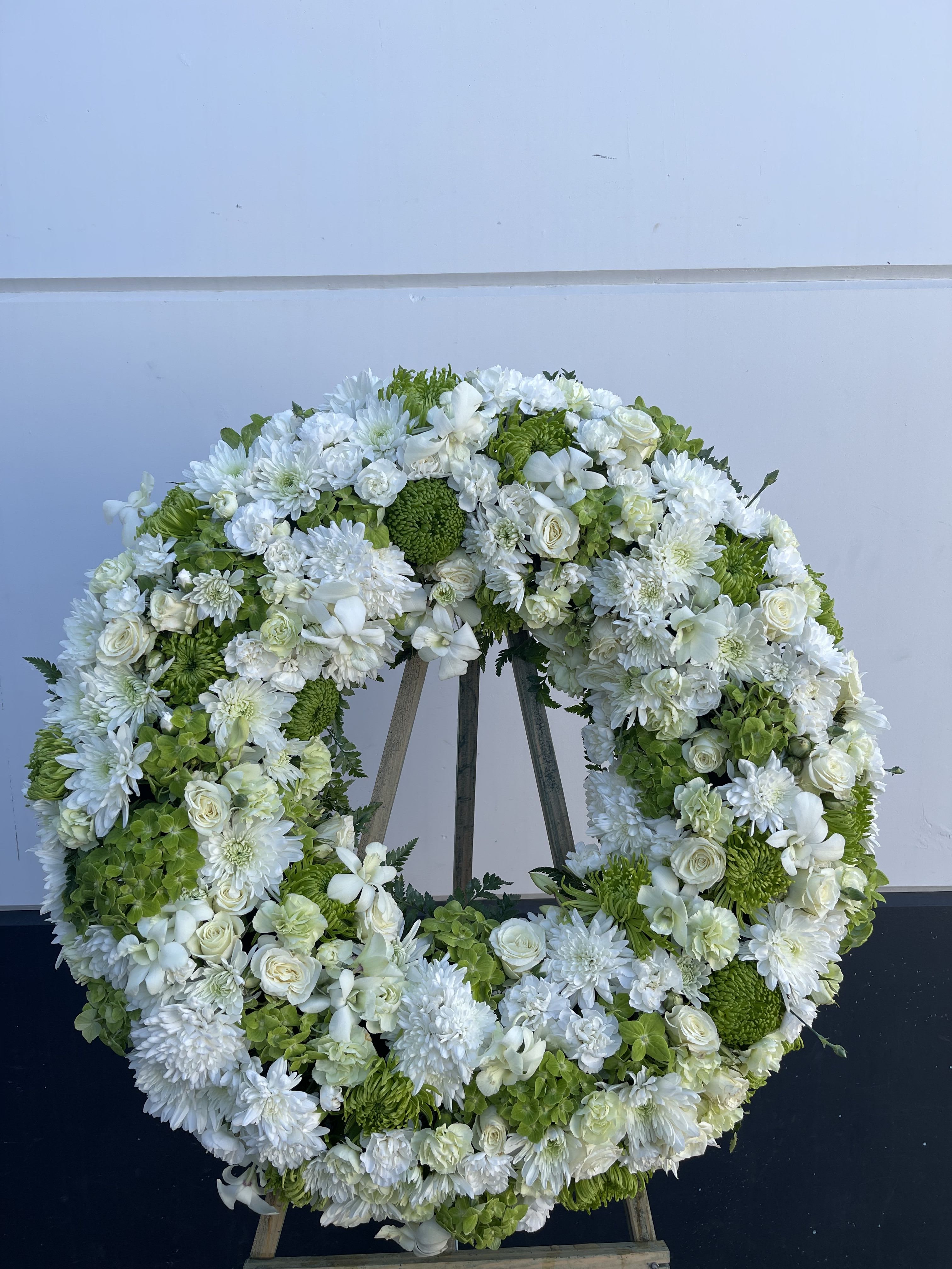 Large white and green floral wreath on an easel