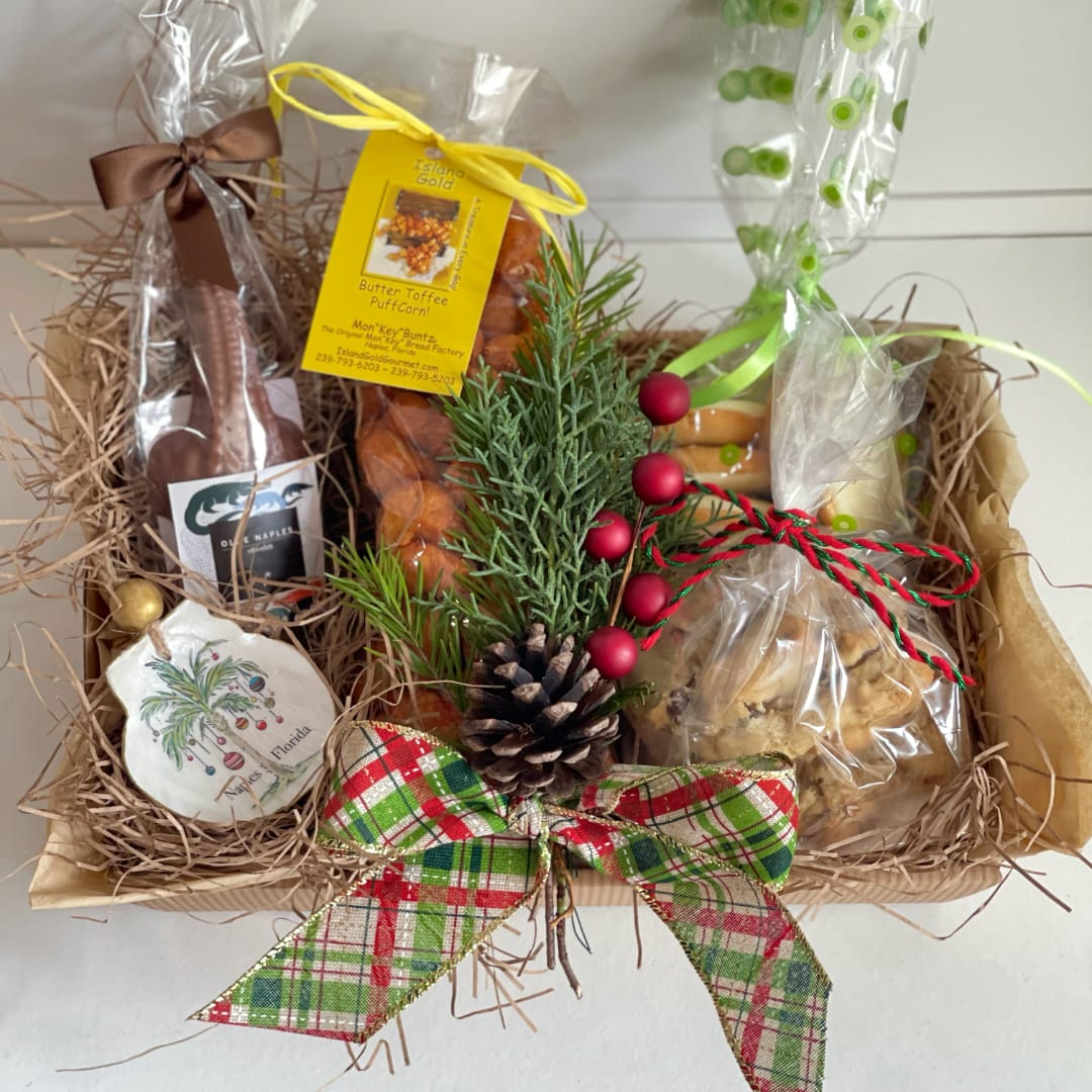 Holiday gift basket with wrapped snacks, pine sprigs, and a plaid bow