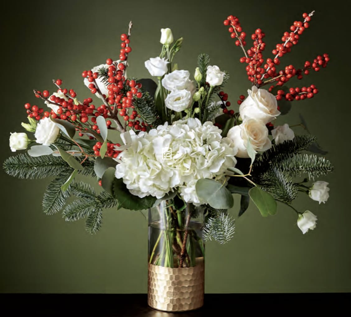 White flowers and red berry branches in a glass vase with a gold base